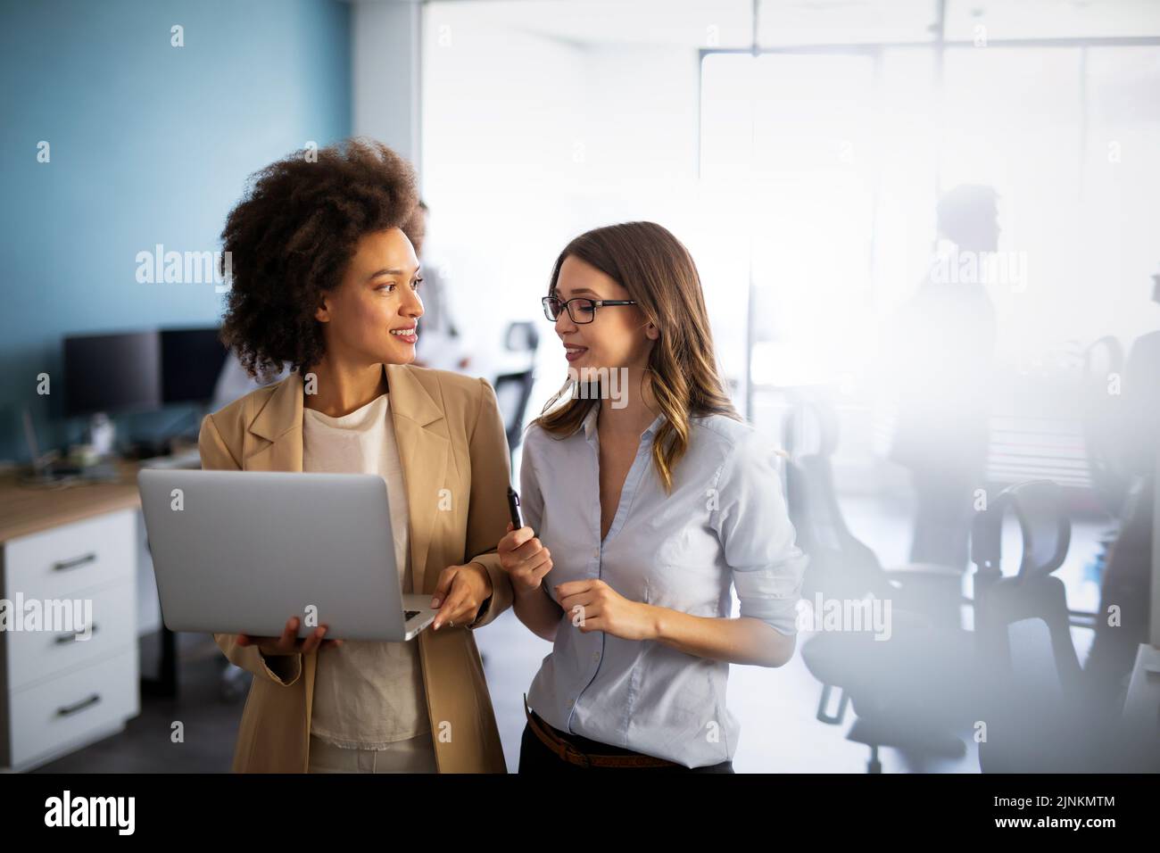 Glückliche, multiethnische Geschäftsfrauen, die online auf einem Laptop im Büro eines Unternehmens zusammenarbeiten. Stockfoto