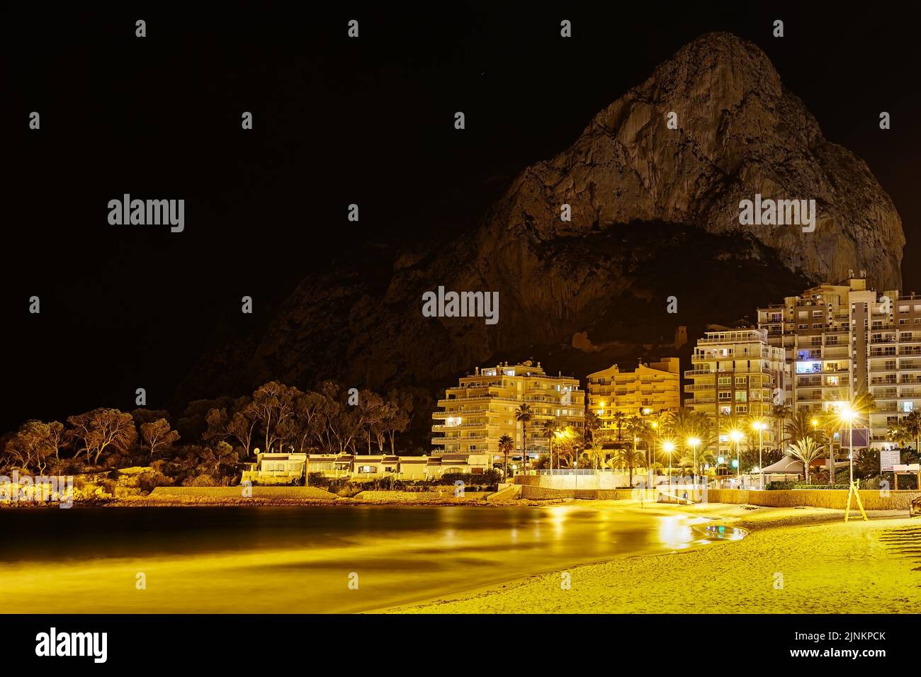 Nächtlicher Strand mit beleuchteten Gebäuden und einem großen Berg im Hintergrund neben dem Meer. Calpe Alicante. Stockfoto