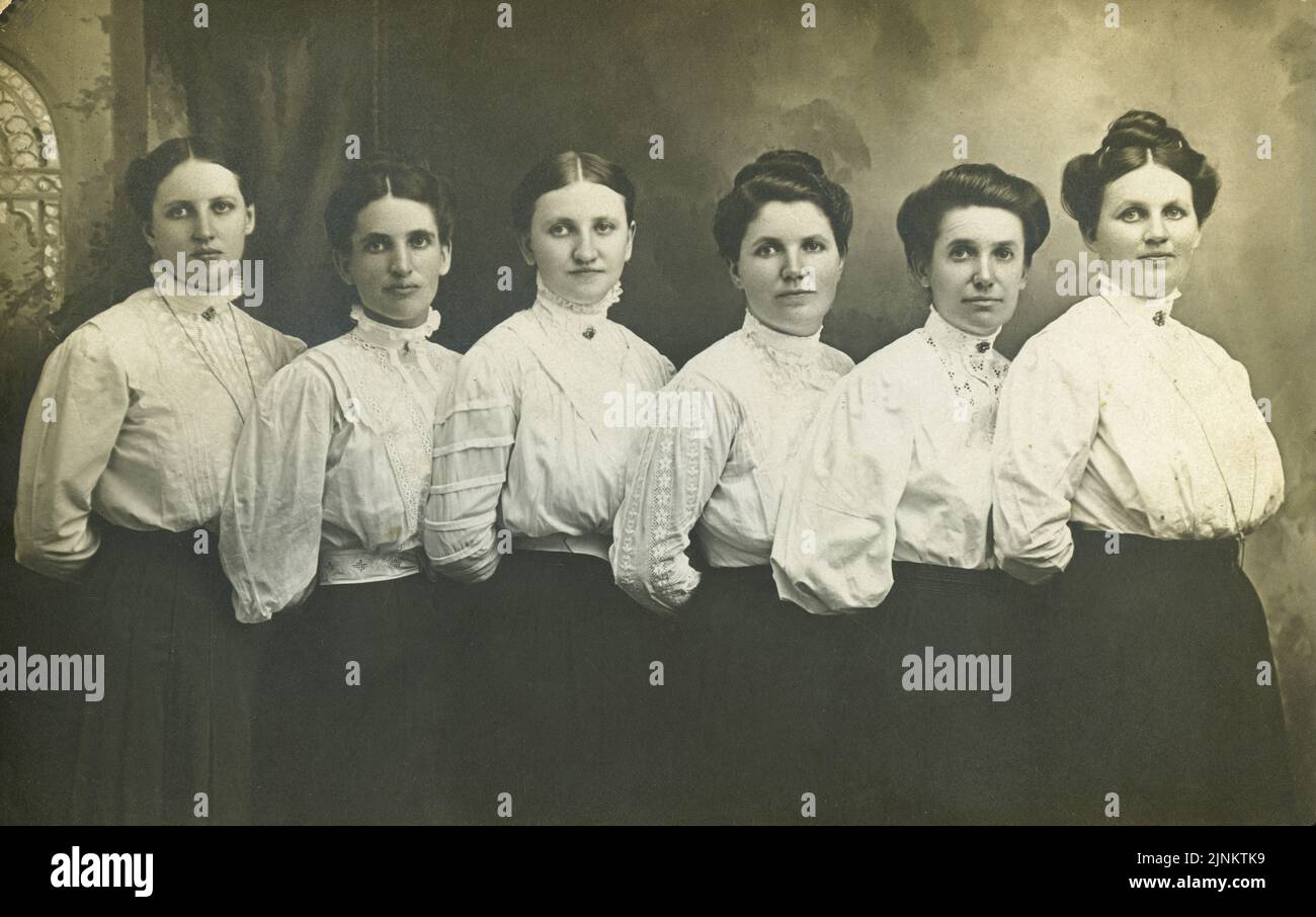 Viktorianisches Schwarz-Weiß-Foto von sechs jungen Frauen in einer Linie für die Kamera mit Gibson Girl Frisur in zeitlicher Kleidung zur Jahrhundertwende von 1890s bis 1900s posiert Stockfoto