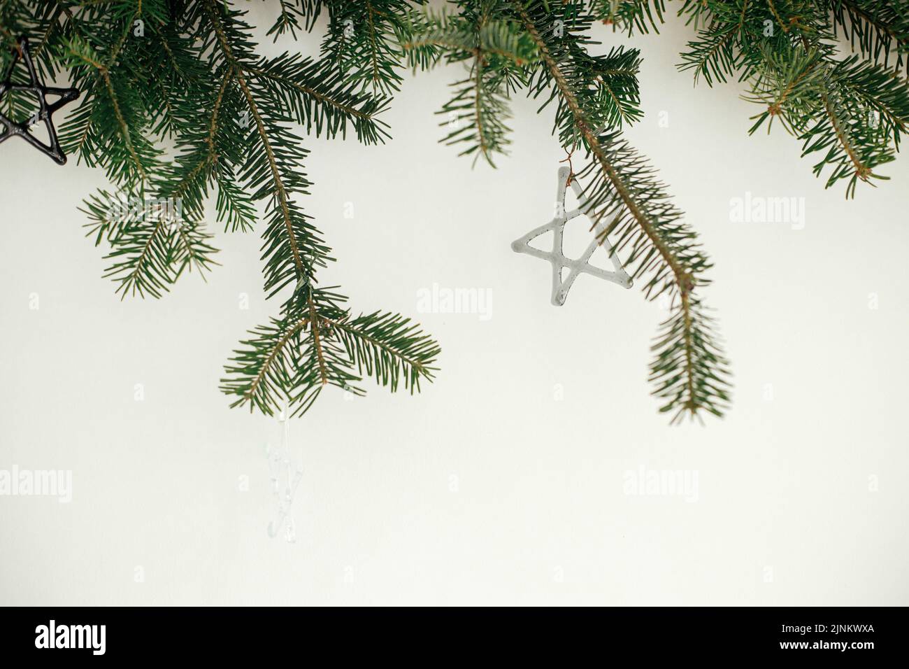 Stilvolle weihnachtsschmuck auf Tannenzweigen vor weißem Hintergrund. Moderne Glaskugeln auf Christbaumzweigen, skandinavische Dekoration in festlicher Form Stockfoto