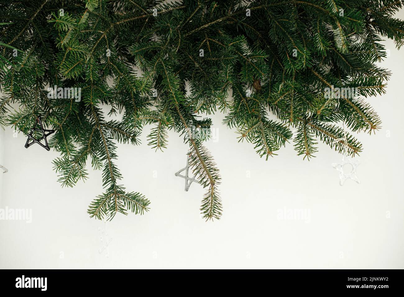 Stilvolle weihnachtsschmuck auf Tannenzweigen vor weißem Hintergrund. Moderne Glaskugeln auf Christbaumzweigen, skandinavische Dekoration in festlicher Form Stockfoto