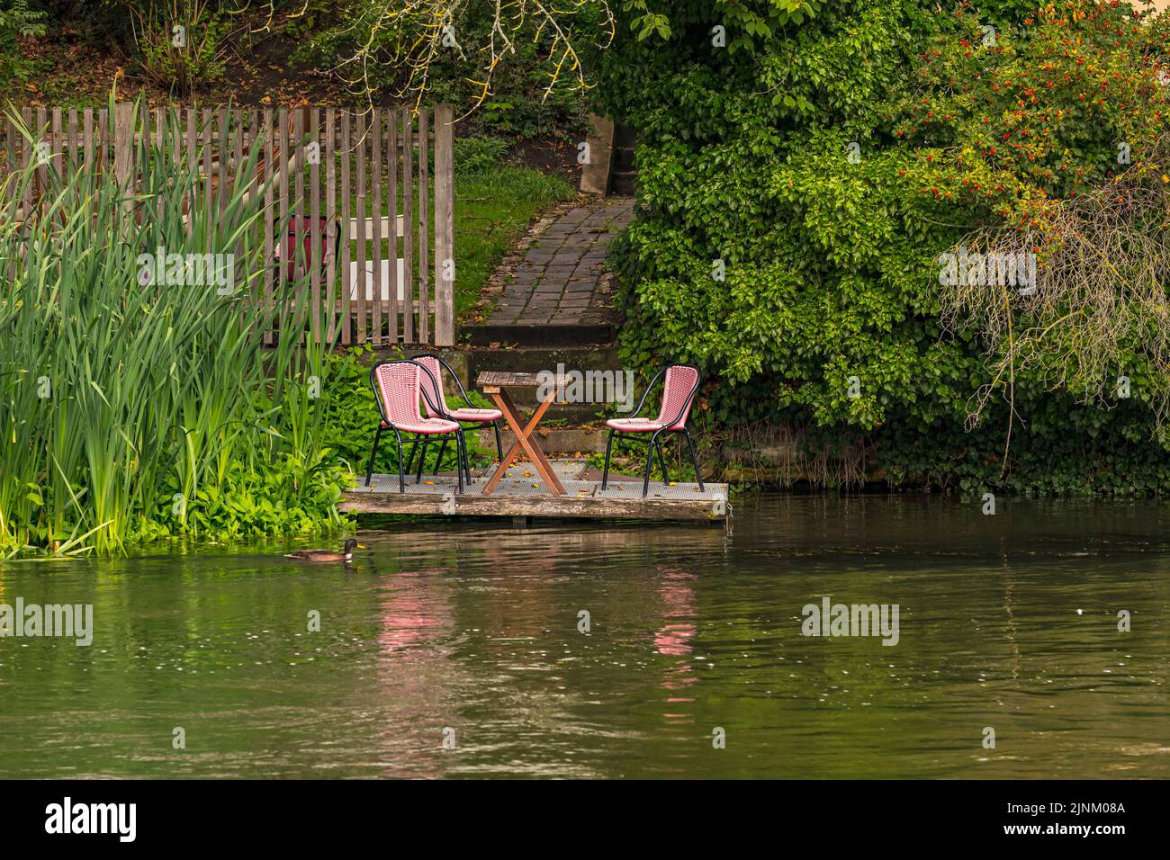 Ein idyllischer Platz mit Tisch und drei Stühlen in Bamberg direkt am Wasser der Regnitz, Deutschland Stockfoto