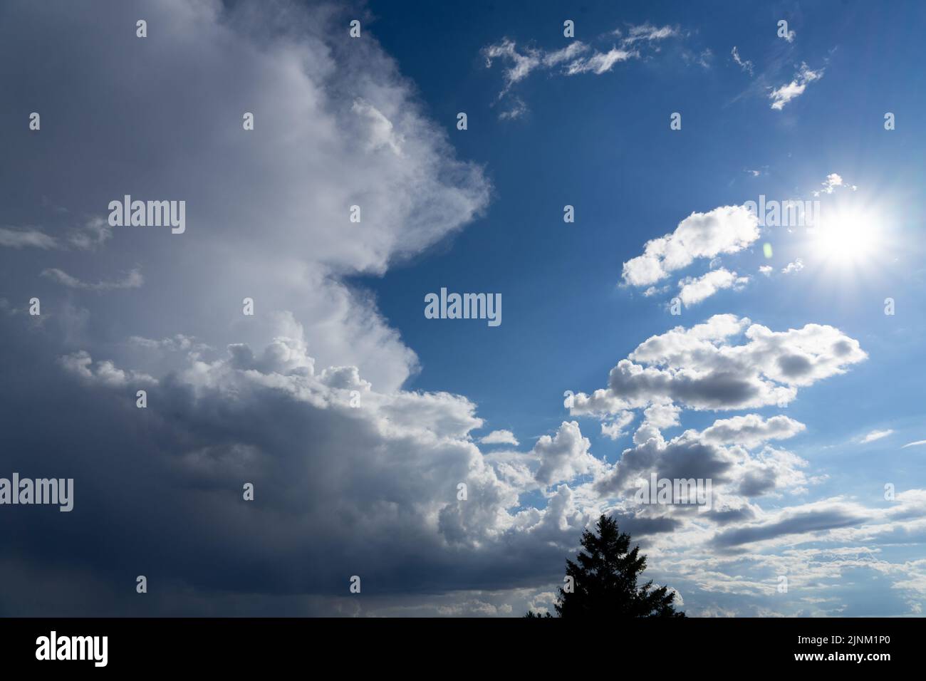 Gewitterwolken ragen in einem strahlend blauen Sommerhimmel auf Stockfoto