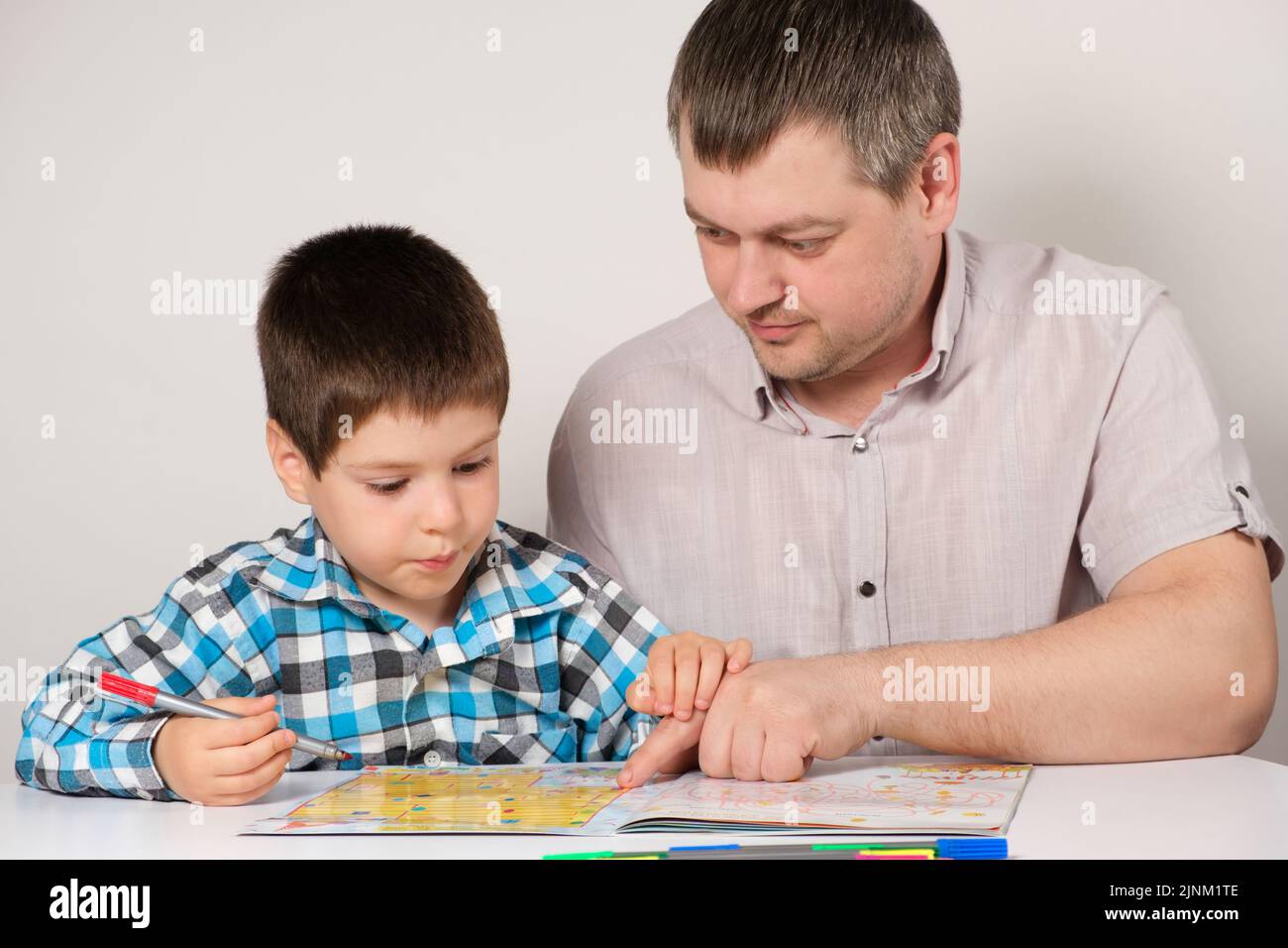 Vater und Sohn durchmachen Labyrinthe, führen Aufgaben für Logik und die Entwicklung des Denkens zur Vorbereitung auf die Schule aus. Stockfoto