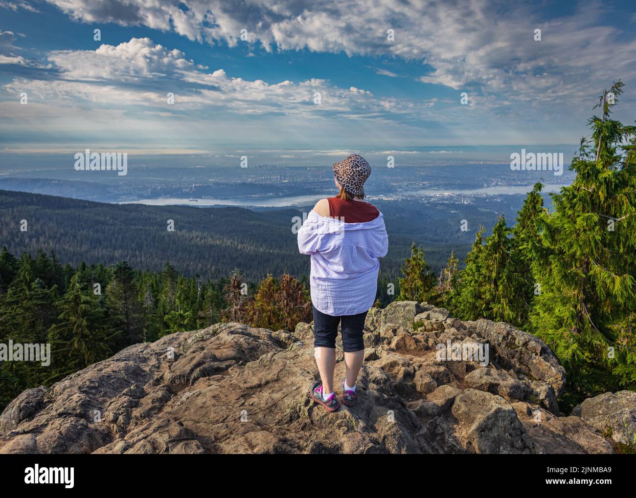 Frau, die am Rand der Klippe steht und den Blick auf das Tal, den Fluss und die Berge genießt. Reisen entlang Kanadas. Platz für Text kopieren, Landschaft c Stockfoto