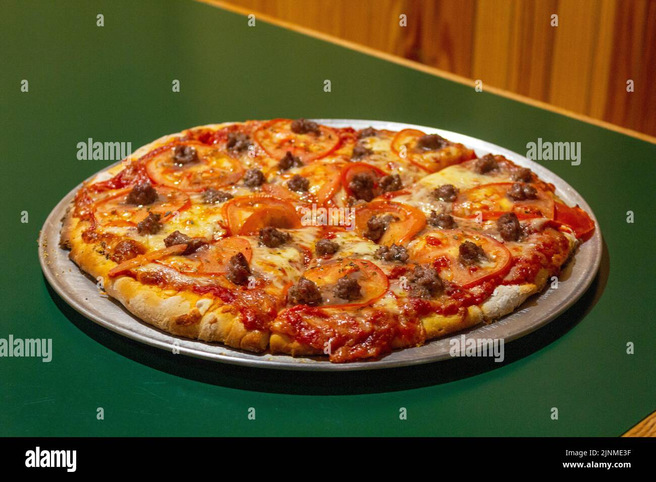 Kitschige Backsteinpizza mit Rindfleisch und Tomaten Stockfoto