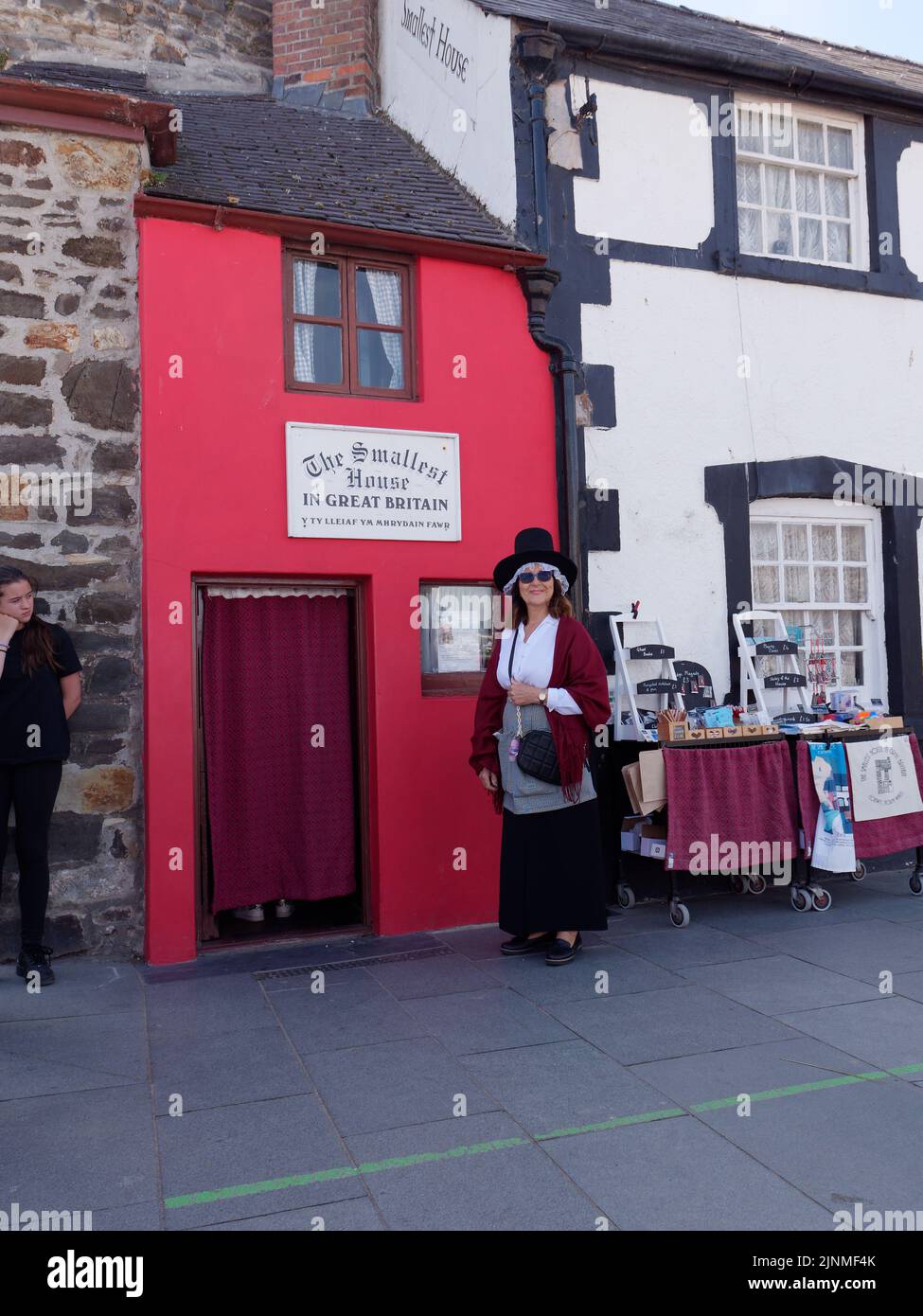 Conwy, Clwyd, Wales, August 07 2022: Lady in a hat steht vor dem kleinsten Haus Großbritanniens. Stockfoto