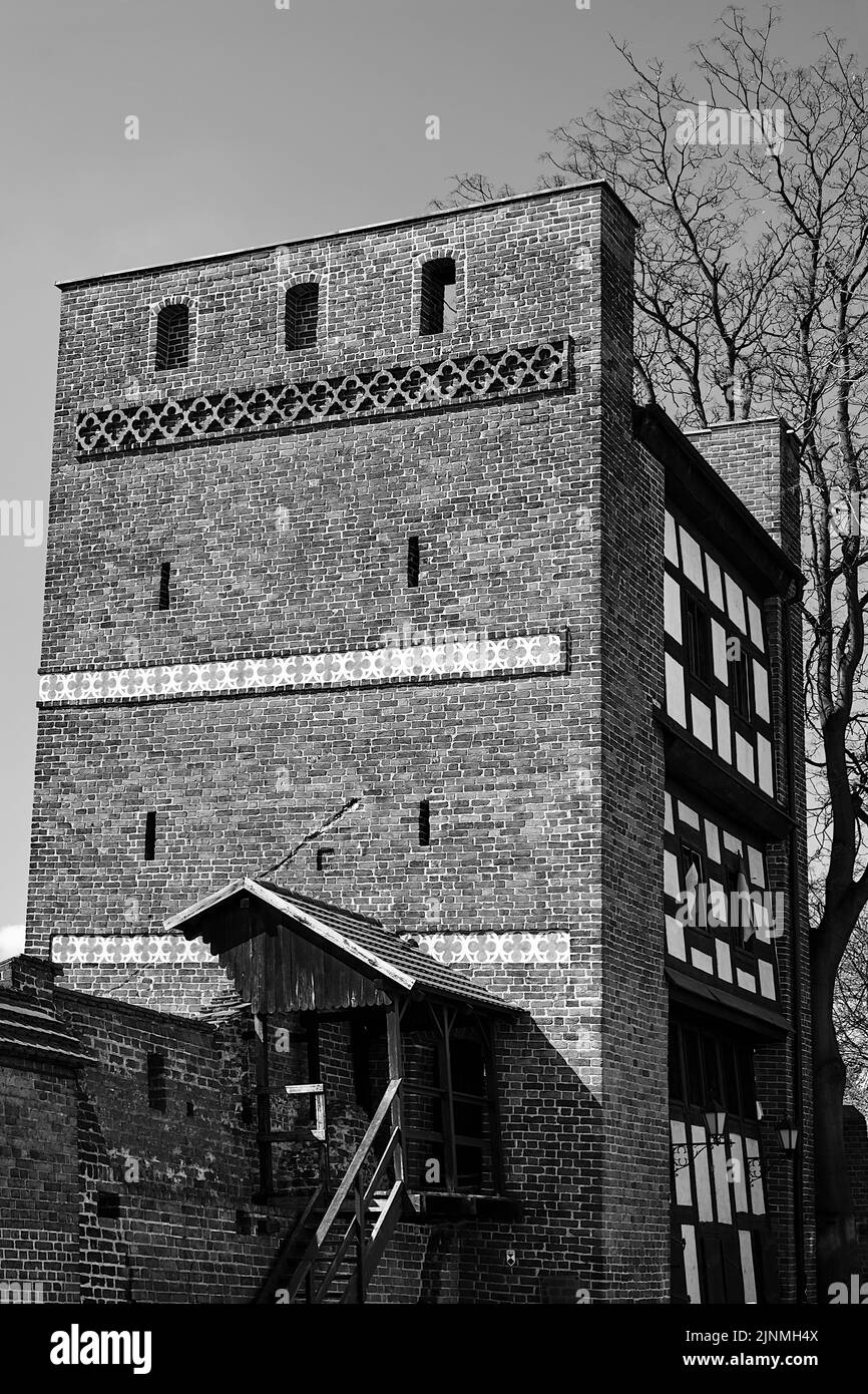 Ein historischer Turm und eine Backsteinmauer in der Stadt Torun in Polen, monochrom Stockfoto