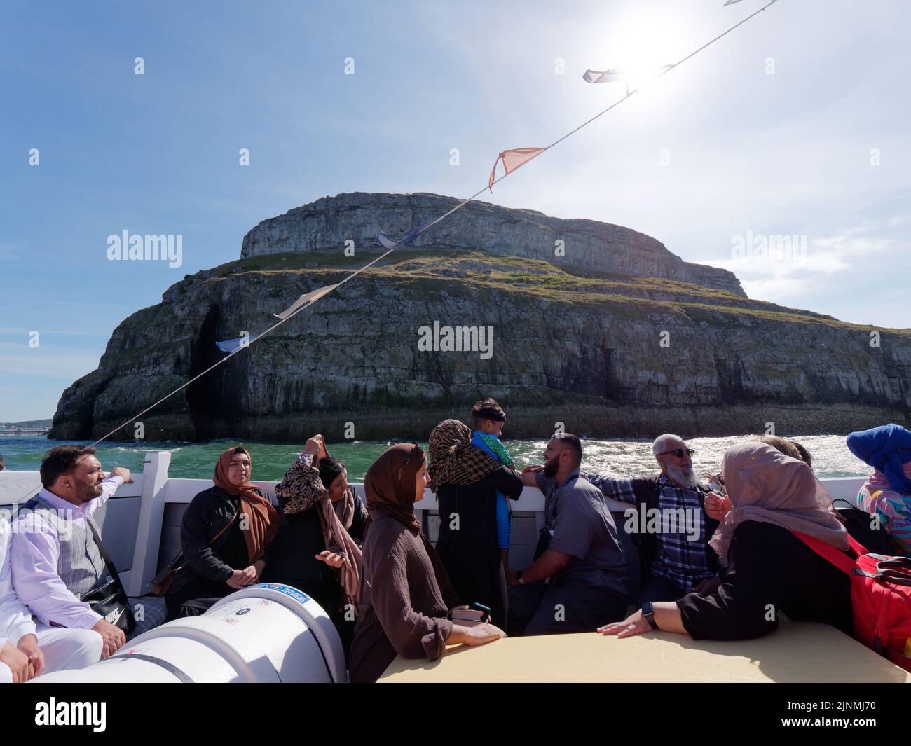 Llandudno, Clwyd, Wales, August 07 2022: Menschen genießen eine Bootsfahrt mit der Great Orme im Hintergrund. Stockfoto