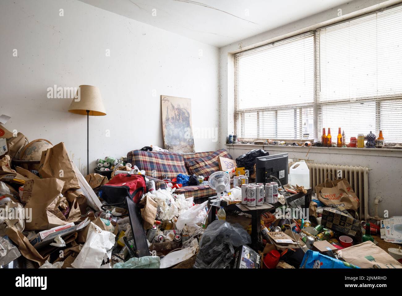 Ein dreckiges Wohnzimmer mit viel Unordnung in einem Apartment eines Hoarders. Dieses Gebäude wurde seitdem abgerissen Stockfoto