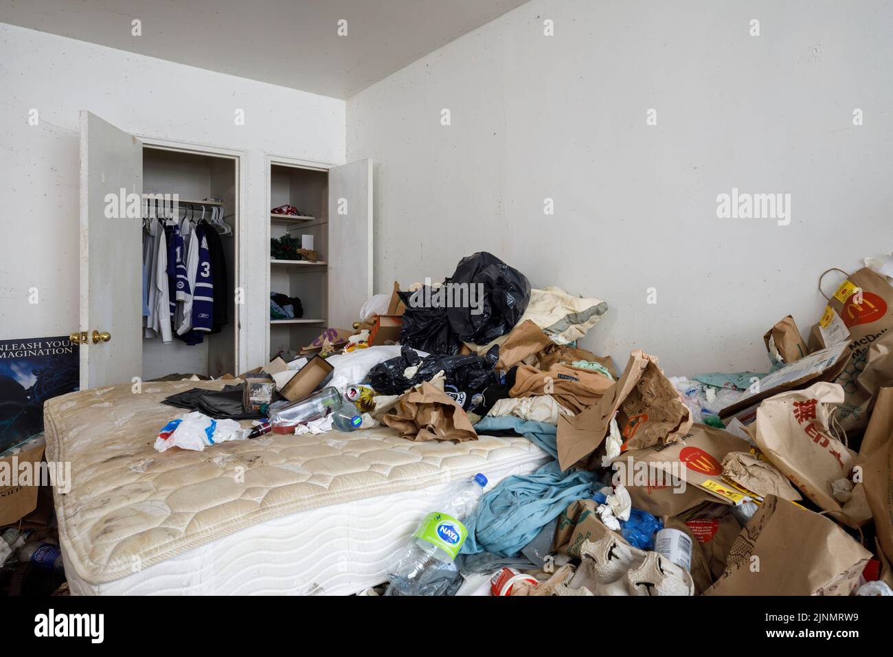 Ein dreckiges Apartment-Schlafzimmer mit viel Unordnung in einem Hoarder-Apartment. Dieses Gebäude wurde seitdem abgerissen Stockfoto