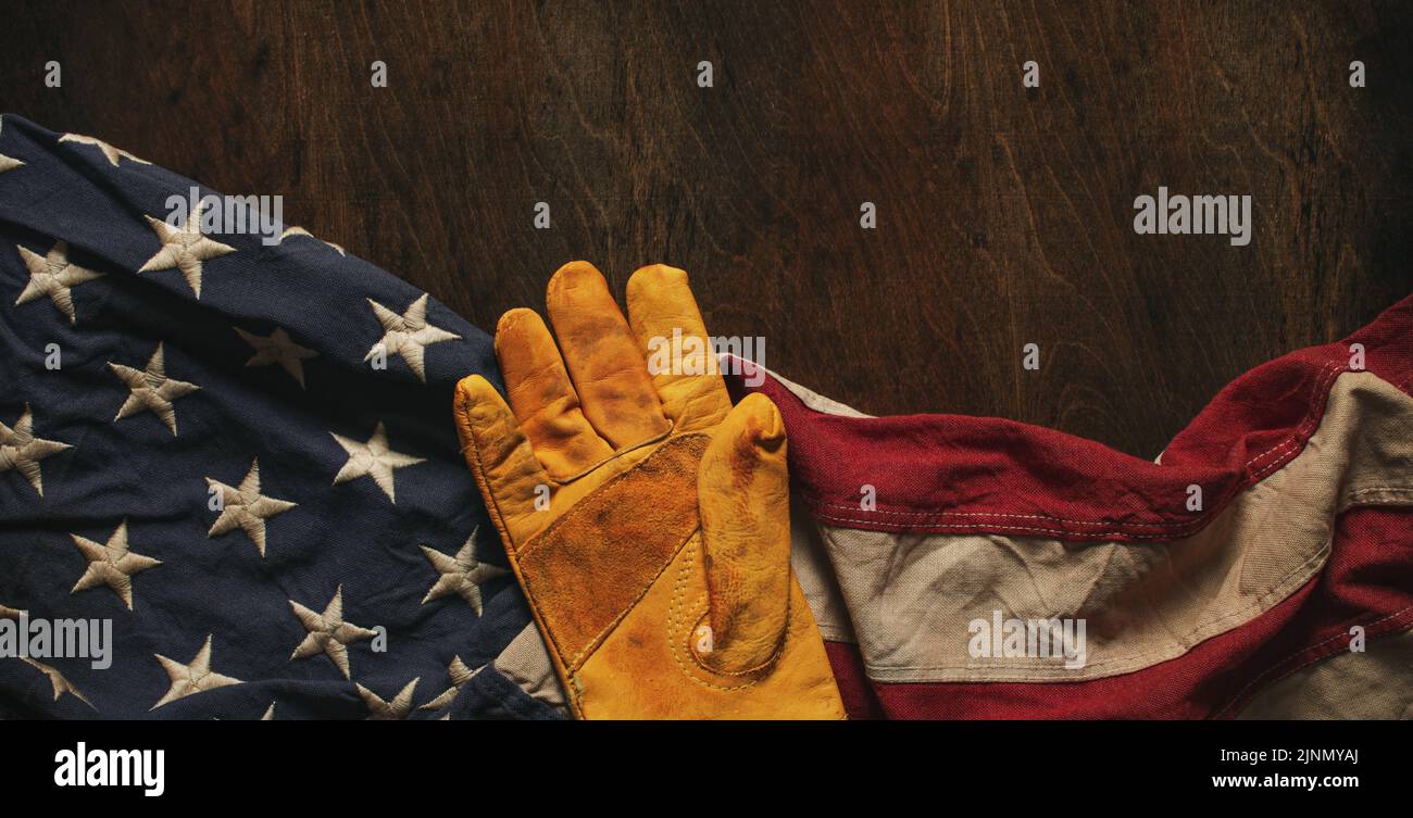 Arbeitshandschuh auf US-amerikanischer Flagge getragen. Made in USA, American Workforce, Blue Collar Worker oder Labor Day Concept. Stockfoto