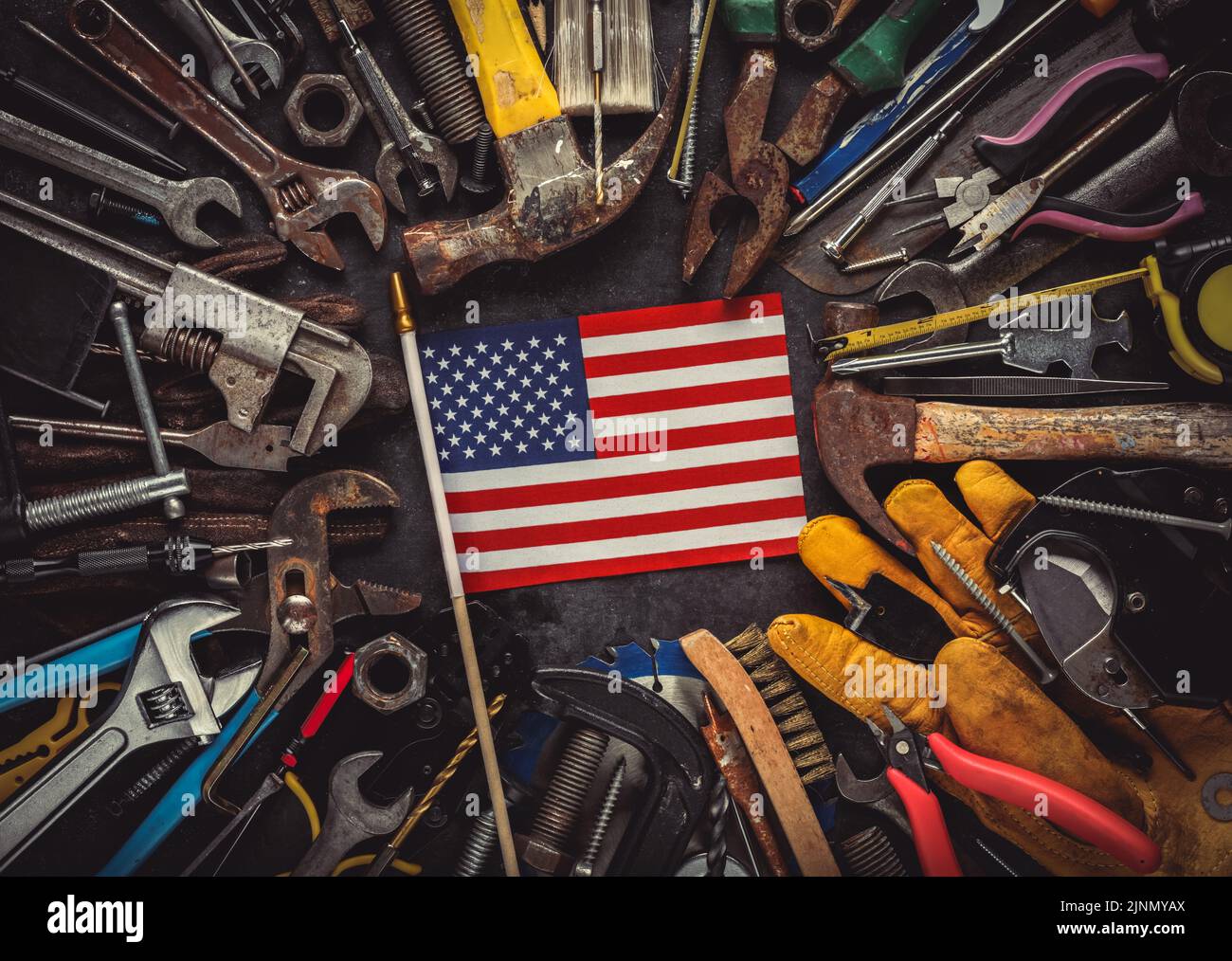 Patriotische Sammlung abgenutzter und gebrauchter Arbeitswerkzeuge mit kleiner US-amerikanischer Flagge. Made in USA, American Workforce oder Labor Day Concept. Stockfoto