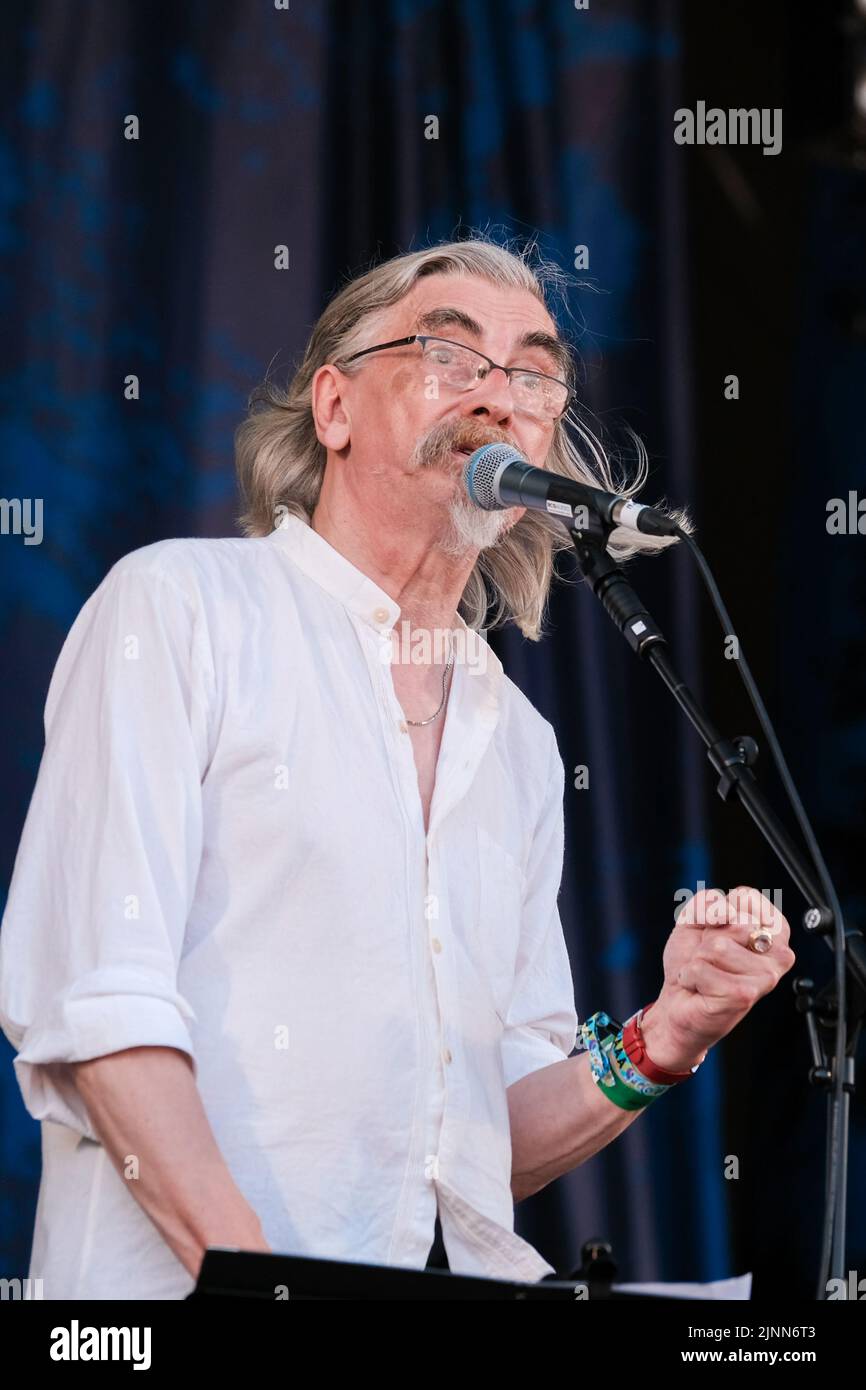 Cropredy, Großbritannien. 12. August 2022. John Tams, englischer Schauspieler, Sänger, Songwriter, Komponist und Musiker und Sohn eines Publikums, ehemaliges Mitglied der Derbyshire Folk-Gruppe Muckram, wacht auf, während die britische Folk-Rock-Gruppe Home Service live auf der Bühne des Cropredy Festivals der Fairport Convention auftrat. Home Service ist eine britische Folk-Rock-Gruppe, die Ende 1980 aus einem Kern von Musikern gegründet wurde, die in Ashley Hutchings' Albion Band gespielt hatten. Ihre Karriere ist allgemein vereinbart, mit dem Album Alright Jack ihren Höhepunkt erreicht zu haben und hat einen Einfluss auf die spätere Arbeit, die John Tams und mehrere andere Mitglieder der Band haben, gehabt Stockfoto
