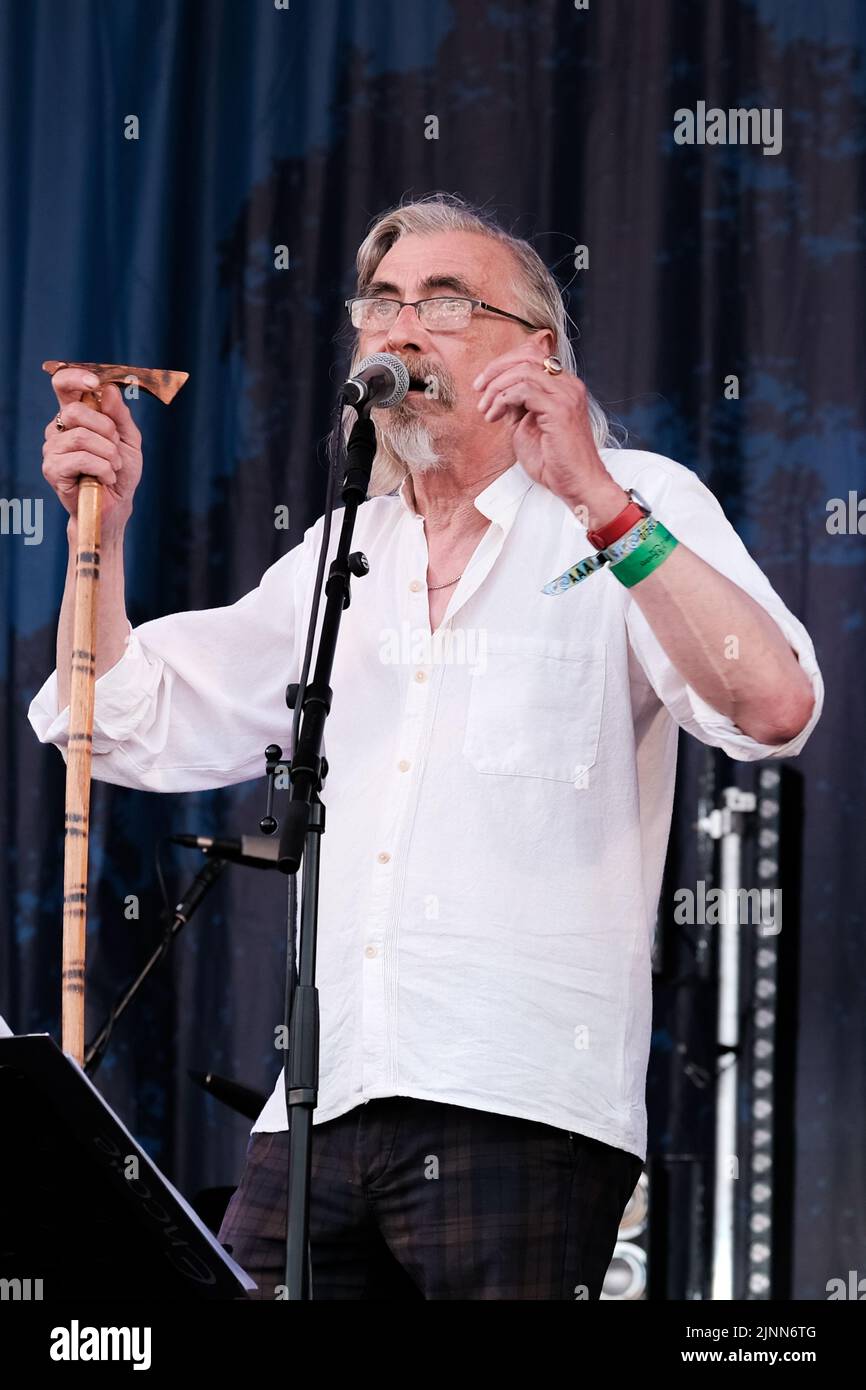 Cropredy, Großbritannien. 12. August 2022. John Tams, englischer Schauspieler, Sänger, Songwriter, Komponist und Musiker und Sohn eines Publikums, ehemaliges Mitglied der Derbyshire Folk-Gruppe Muckram, wacht auf, während die britische Folk-Rock-Gruppe Home Service live auf der Bühne des Cropredy Festivals der Fairport Convention auftrat. Home Service ist eine britische Folk-Rock-Gruppe, die Ende 1980 aus einem Kern von Musikern gegründet wurde, die in Ashley Hutchings' Albion Band gespielt hatten. Ihre Karriere ist allgemein vereinbart, mit dem Album Alright Jack ihren Höhepunkt erreicht zu haben und hat einen Einfluss auf die spätere Arbeit, die John Tams und mehrere andere Mitglieder der Band haben, gehabt Stockfoto