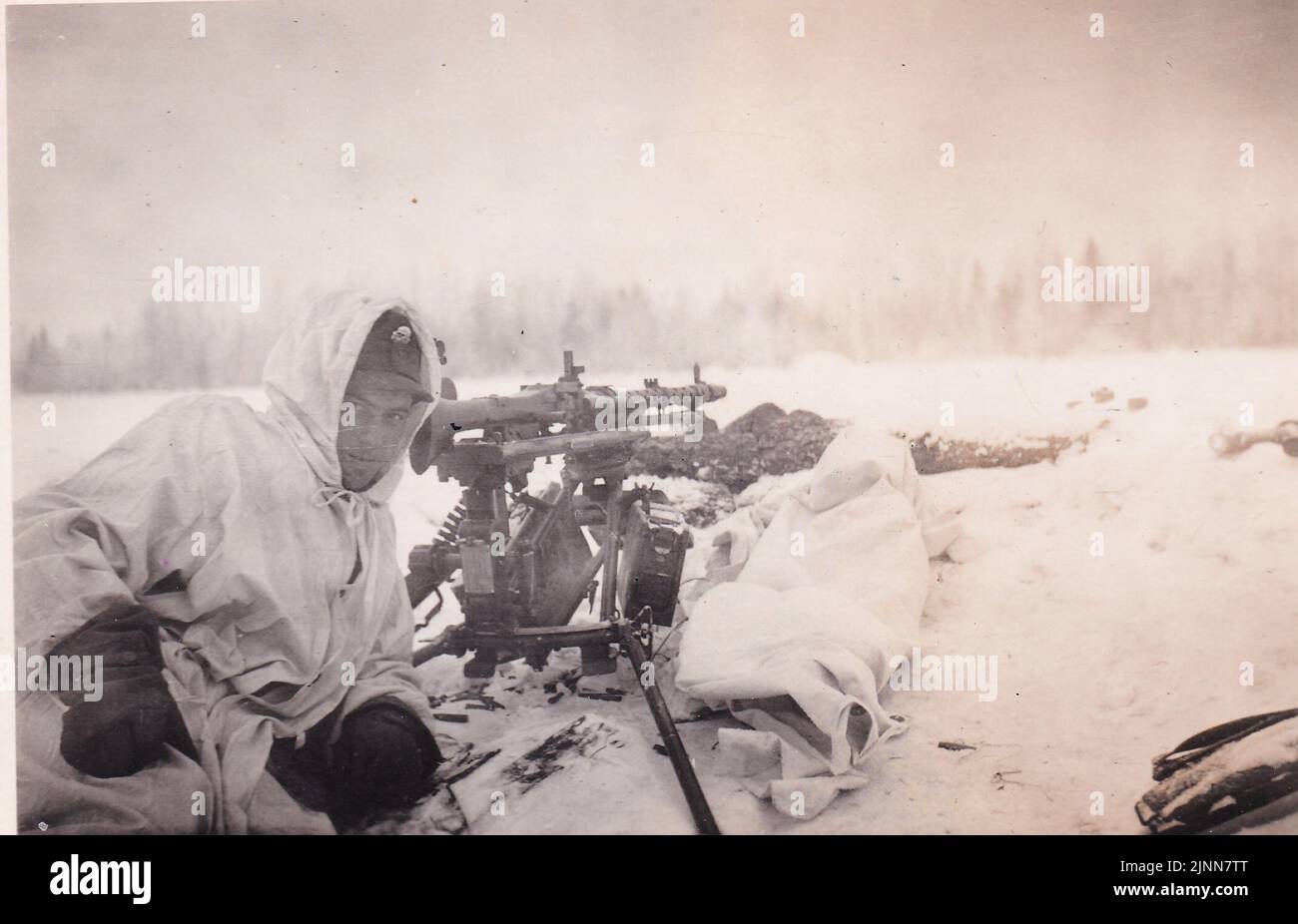 World war Two B&W Foto Deutsche Waffen SS Mann lächelt vor die Kamera hinter einer MG34 an der russischen Front im Jahr 1942 . Der SS-Mann trägt ein Snow Camo, um sich in das verschneite Gelände einzufügen. Stockfoto