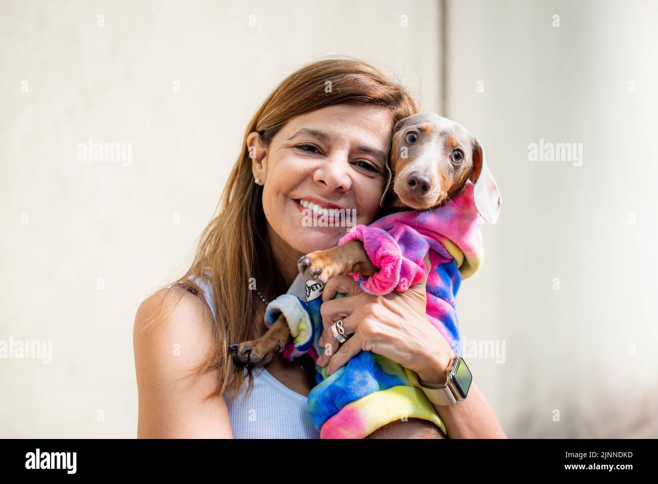 Lateinische Frau mit ihrem Hund. Beide sind gleich gekleidet und blicken in die Kamera Stockfoto