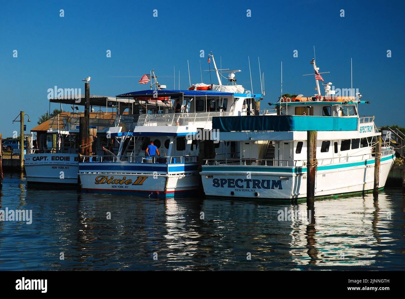 Die Charterflotte der Fischerboote im Captree State Park auf Long Island spiegelt sich im ruhigen Wasser des Hafens wider Stockfoto