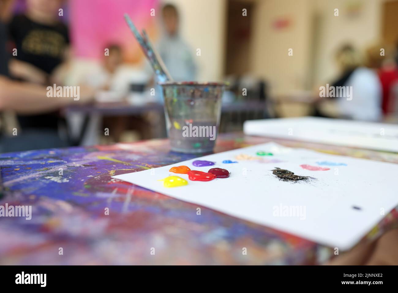 Malen Sie Pinsel in Gläsern und bunte Farben auf weißem Blatt Papier Stockfoto