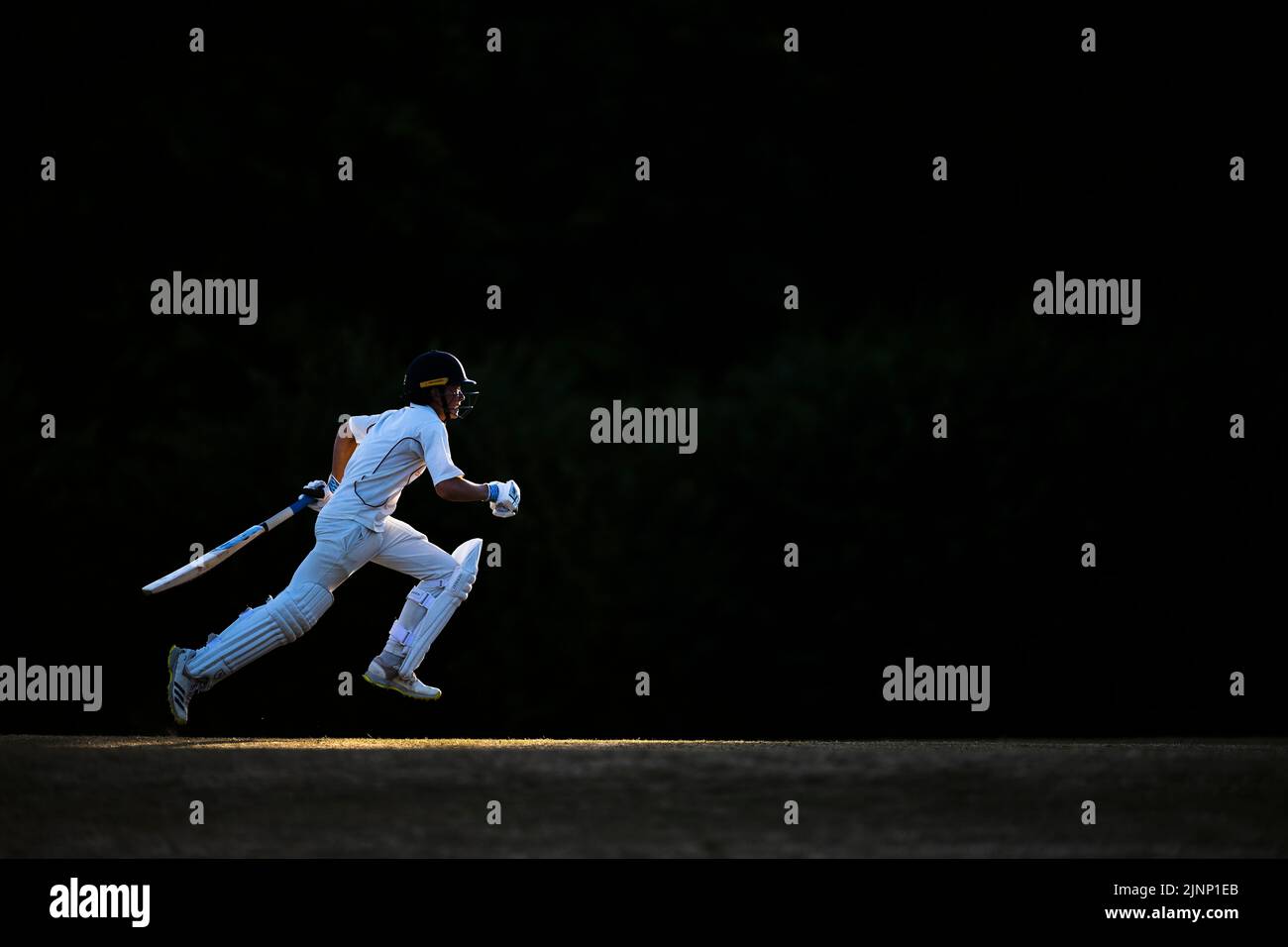 Junior Batsman läuft Stockfoto