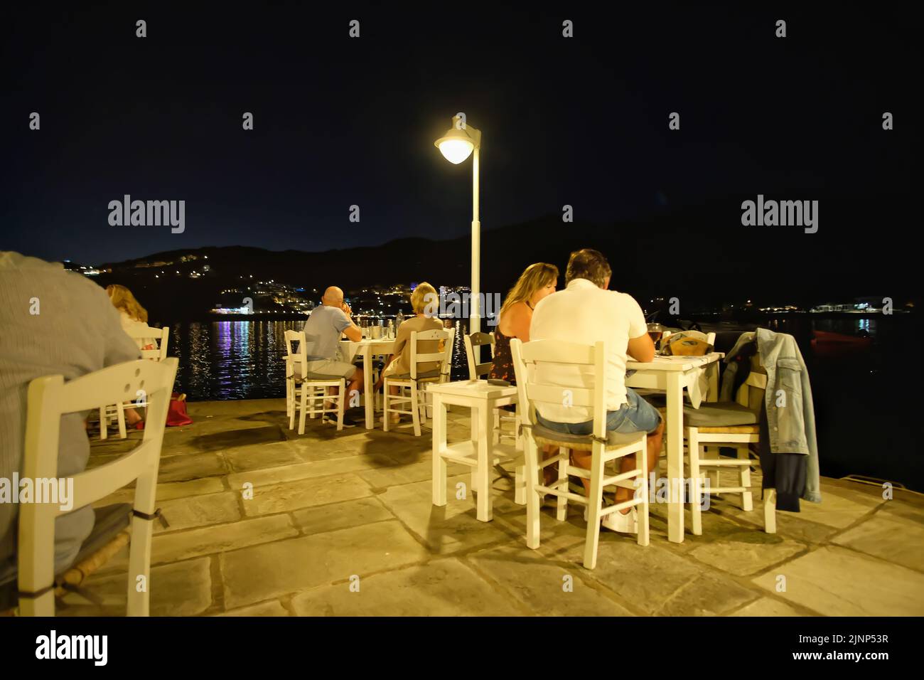 IOS, Griechenland - 8. Juni 2021 : Touristen genießen köstliche Fischgerichte in einer traditionellen griechischen Taverne am Meer in der Nacht in iOS Griechenland Stockfoto