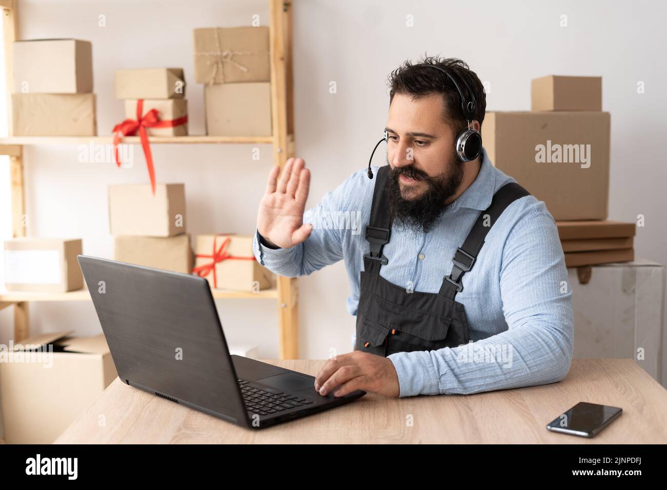 indischer bärtiger Geschäftsmann mit Online-Videoanruf mit Kunden auf dem Laptop und Kopfhörer. Konzentrierter tausendjähriger Mann, der Online-Vortrag hält Stockfoto