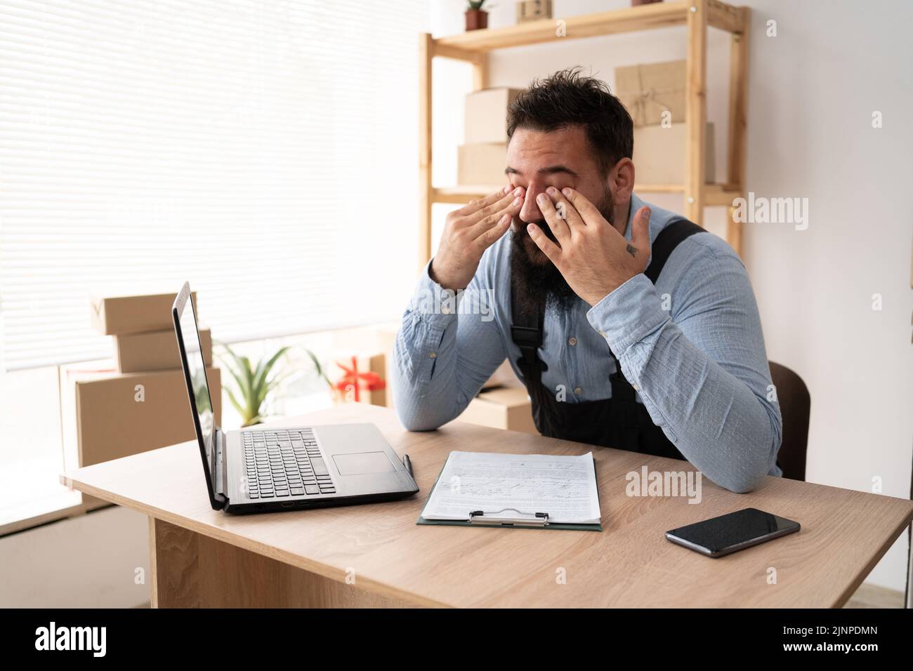 Müde indische männliche Kleinunternehmer arbeiten am Laptop, Online-Shop Delivery Worker hat Vision Probleme, Geschäftsmann arbeiten im Home Office, kmu Stockfoto