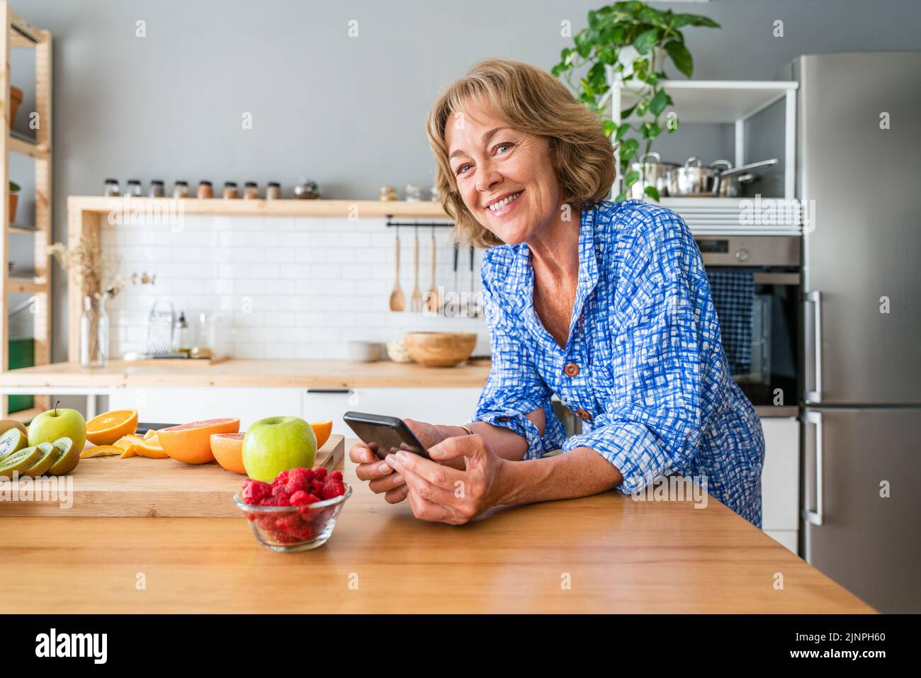Schöne reife ältere Frau zu Hause, häusliches Leben und Freizeit Momente - 50-60 Jahre alt hübsche weibliche Erwachsene mit Smartphone im Web surfen Stockfoto