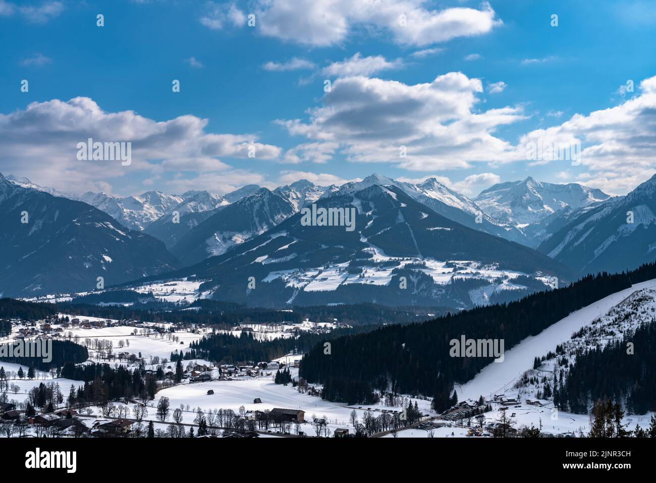 Schöne Luftpanoramabsicht von Ramsau am Dachstein Dorf und Schladming mit Planai und anderen Gipfeln der Alpen im Hintergrund mit blauer Himmelswolke in Stockfoto