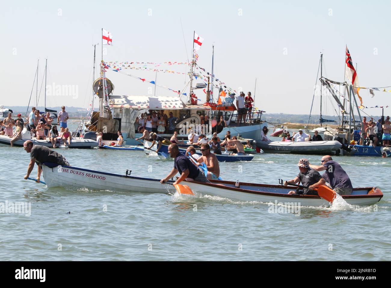 West Mersea, Großbritannien. 13. August 2022. Die West Mersea Regatta findet auf Mersea Island statt. Die Regatta wird seit 1838 fast ununterbrochen durchgeführt und wird von Freiwilligen organisiert. Die drei in einem Boot Schaufel Rennen. Kredit: Eastern Views/Alamy Live Nachrichten Stockfoto