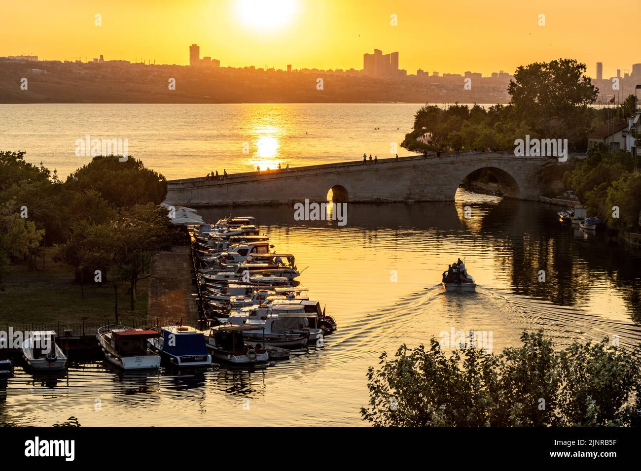 Kucukcekmece, Istanbul, Türkei - Juni 29 2022: Steinbrücke und Fischerboote am See im Stadtteil Kucukcekmece in Istanbul. Bei Sonnenuntergang Stockfoto