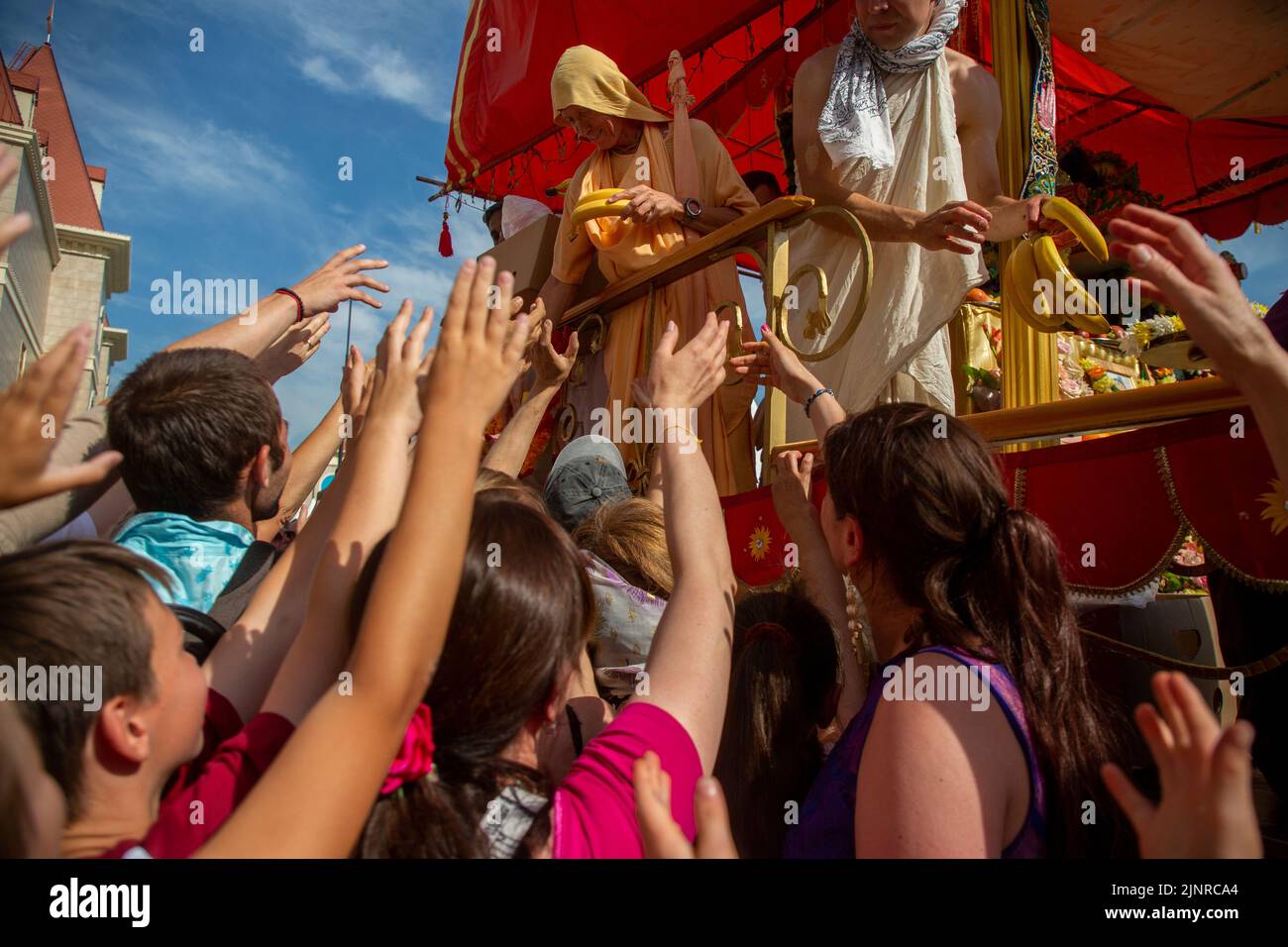 Moskau, Russland. 13. vom August 2022. Сlergy gibt während der Hare Krishna Ratha Yatra Parade oder des Hindu Religious Chariot Festivals im Rahmen des India Day Festivals im Dream Island Park, Russland, exotische Früchte an Anhänger des Hauptwagenwagens aus Stockfoto Moskau, Russland. 13. vom August 2022. Сlergy gibt während der Hare Krishna Ratha Yatra Parade oder des Hindu Religious Chariot Festivals im Rahmen des India Day Festivals im Dream Island Park, Russland, exotische Früchte an Anhänger des Hauptwagenwagens aus Stockfoto
