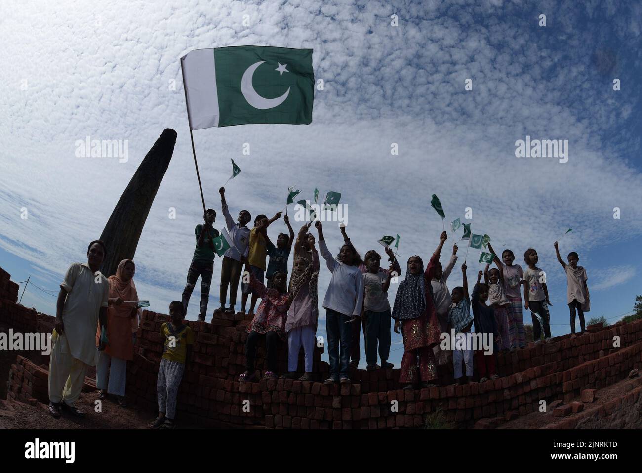 Lahore, Punjab, Pakistan. 12. August 2022. Die Kinder und Arbeiter der United Social Welfare Society von pakistanischen Ziegelöfen feiern den Unabhängigkeitstag 75. am Ziegelofen in Lahore. Der Unabhängigkeitstag (Y?um-e-?z?di), der jährlich am 14. August begangen wird, ist ein Nationalfeiertag in Pakistan. Es erinnert an den Tag, an dem Pakistan seine Unabhängigkeit erlangte und nach dem Ende des britischen Raj im Jahr 1947 zum souveränen Staat erklärt wurde. Pakistan entstand durch die Pakistan-Bewegung, die auf die Schaffung eines unabhängigen muslimischen Staates in den nordwestlichen Regionen abzielte Stockfoto