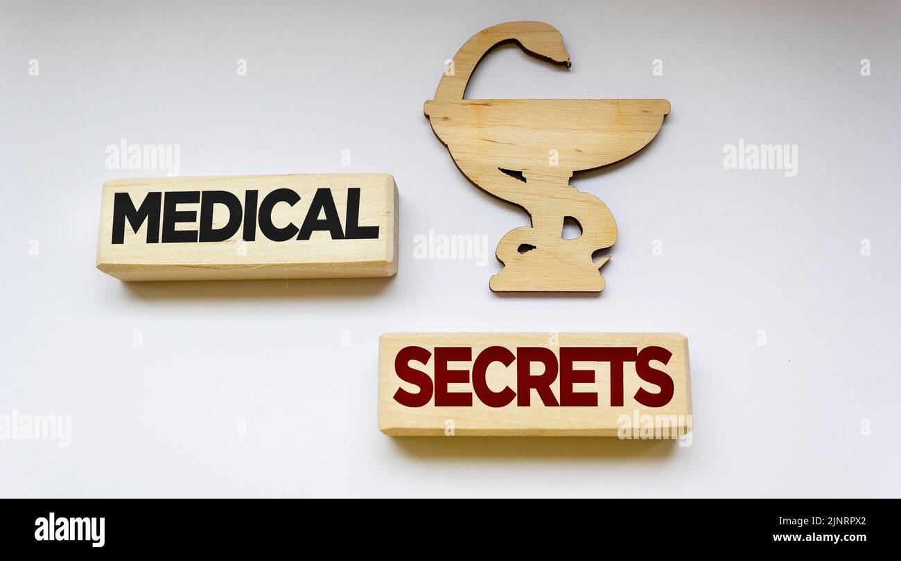 Medizinisches Konzept. Neben dem Symbol der Medizin, Holzblöcke mit der Inschrift - Geheimnisse der Medizin auf weißem Hintergrund Stockfoto