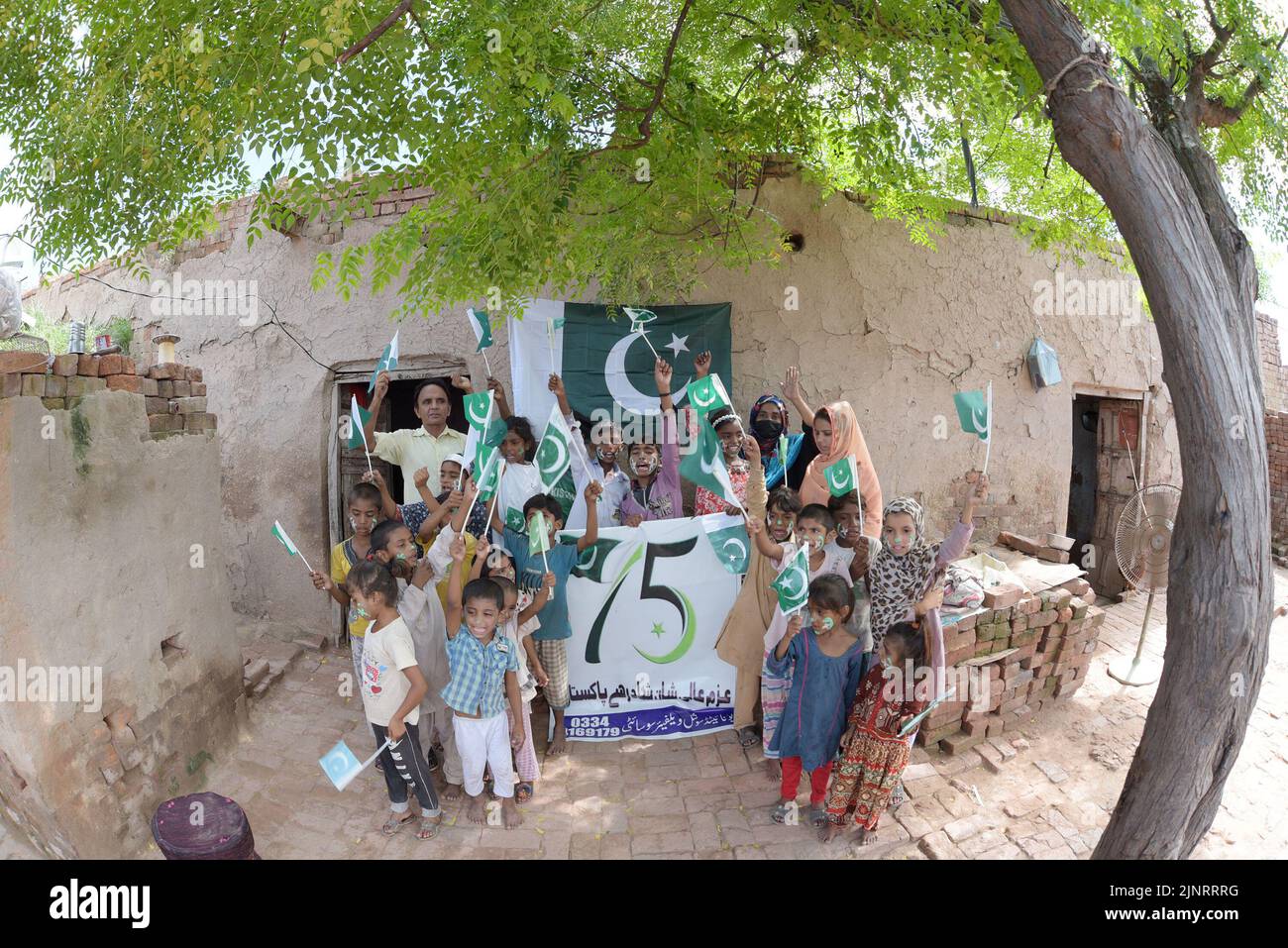 Lahore, Punjab, Pakistan. 12. August 2022. Die Kinder und Arbeiter der United Social Welfare Society von pakistanischen Ziegelöfen feiern den Unabhängigkeitstag 75. am Ziegelofen in Lahore. Der Unabhängigkeitstag (Y?um-e-?z?di), der jährlich am 14. August begangen wird, ist ein Nationalfeiertag in Pakistan. Es erinnert an den Tag, an dem Pakistan seine Unabhängigkeit erlangte und nach dem Ende des britischen Raj im Jahr 1947 zum souveränen Staat erklärt wurde. Pakistan entstand durch die Pakistan-Bewegung, die auf die Schaffung eines unabhängigen muslimischen Staates in den nordwestlichen Regionen abzielte Stockfoto