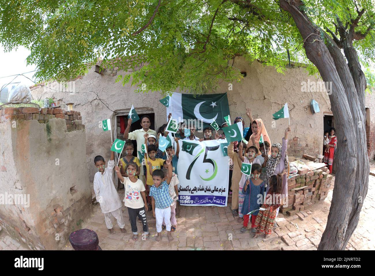 Lahore, Punjab, Pakistan. 12. August 2022. Die Kinder und Arbeiter der United Social Welfare Society von pakistanischen Ziegelöfen feiern den Unabhängigkeitstag 75. am Ziegelofen in Lahore. Der Unabhängigkeitstag (Y?um-e-?z?di), der jährlich am 14. August begangen wird, ist ein Nationalfeiertag in Pakistan. Es erinnert an den Tag, an dem Pakistan seine Unabhängigkeit erlangte und nach dem Ende des britischen Raj im Jahr 1947 zum souveränen Staat erklärt wurde. Pakistan entstand durch die Pakistan-Bewegung, die auf die Schaffung eines unabhängigen muslimischen Staates in den nordwestlichen Regionen abzielte Stockfoto