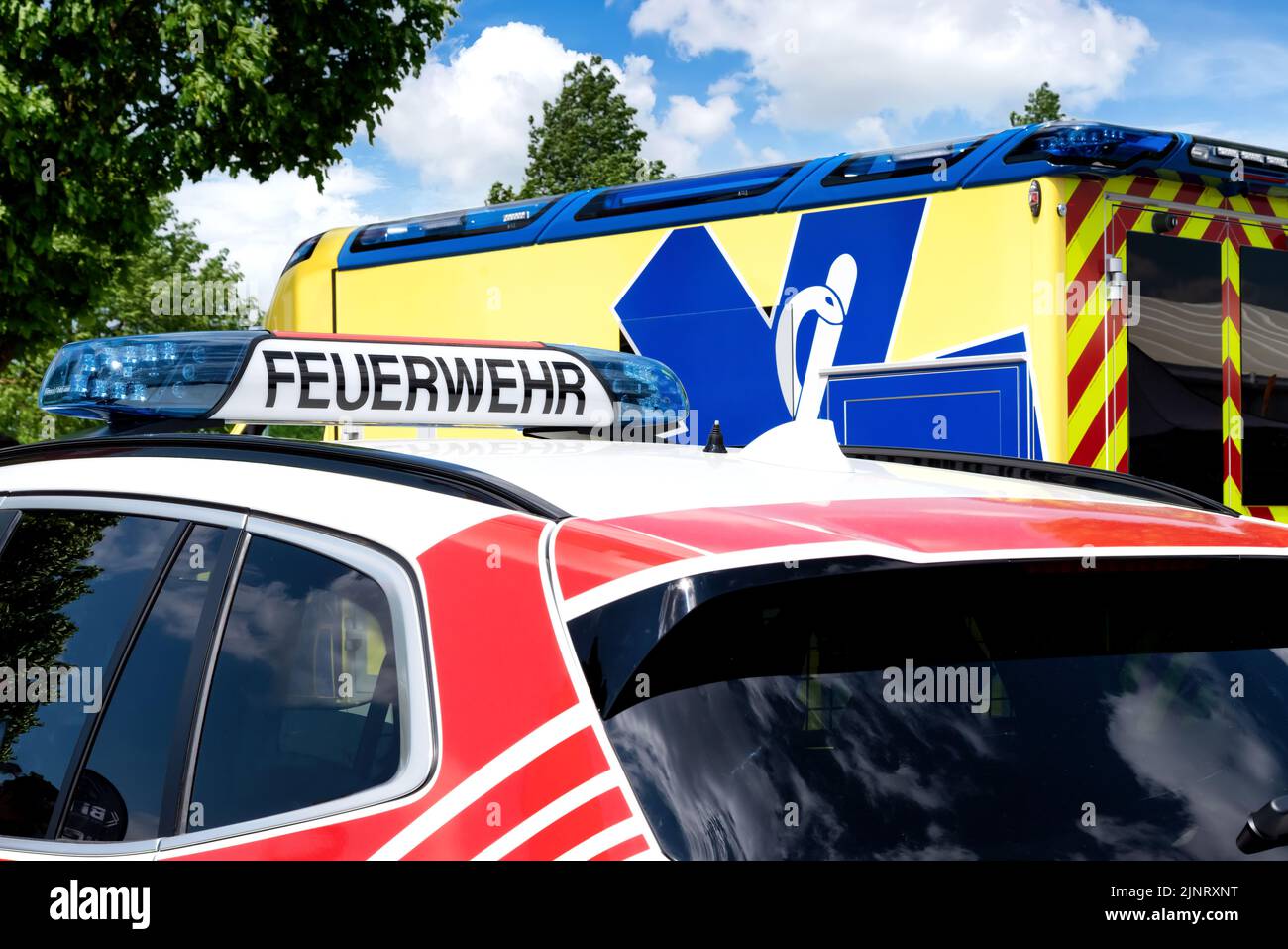 Teilansicht eines Feuerwehrfahrzeugs, im Hintergrund ein Schweizer Notarztfahrzeug. Notruf 112 Stockfoto
