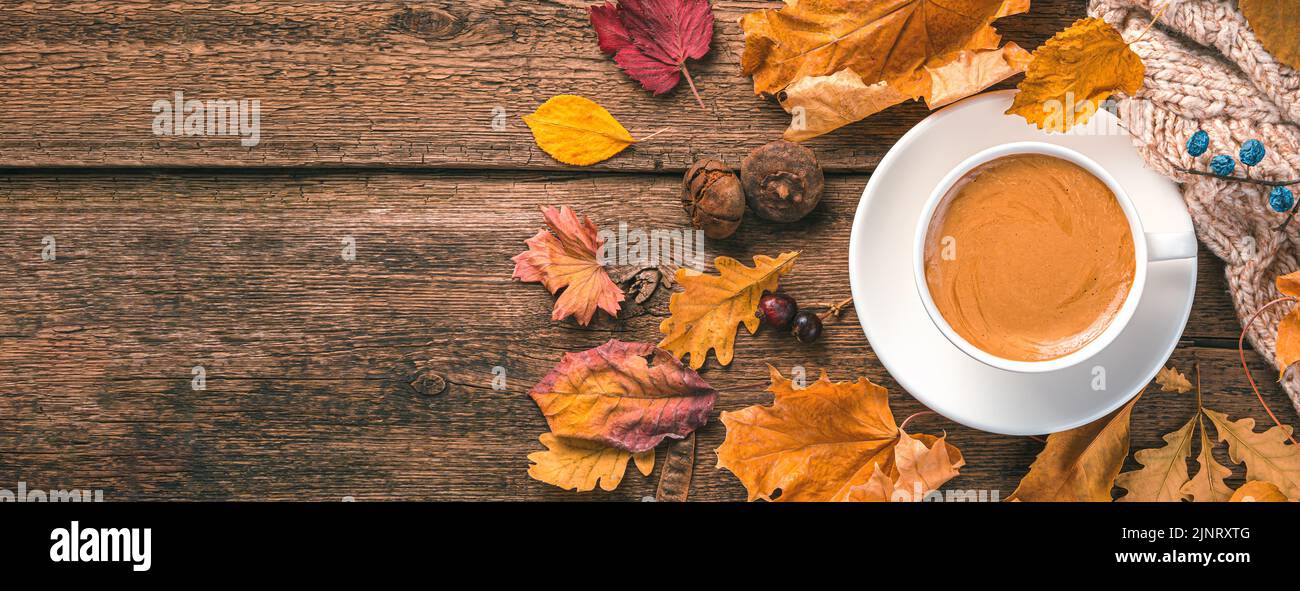 Kaffeetasse, Pullover und Laub auf Holzhintergrund. Draufsicht, Kopierbereich. Stockfoto