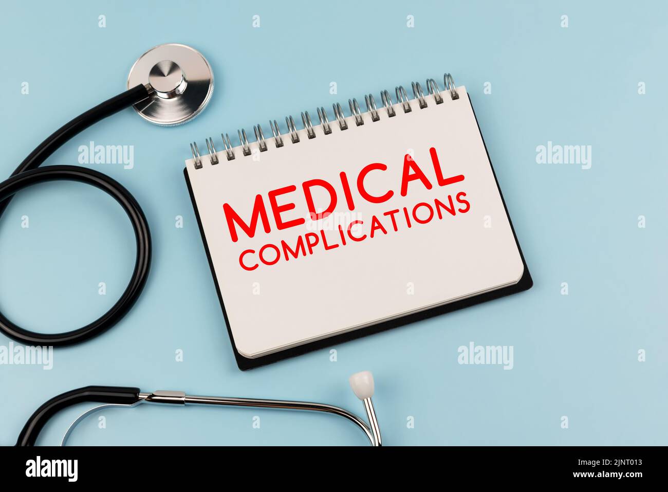 Text zu medizinischen Komplikationen auf Notizblock und Stethoskop Stockfoto