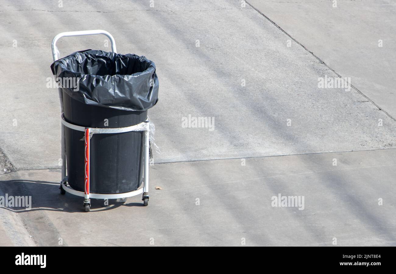 Auf einer sonnigen Straße steht ein mobiler Abfalleimer auf Rädern Stockfoto
