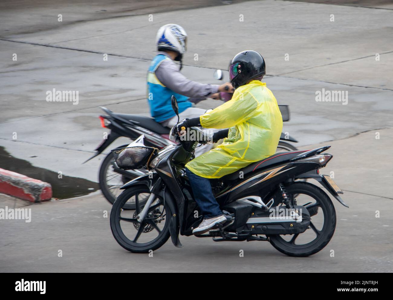 Die Moto-Taxifahrer fahren auf einer nassen Straße, Thailand Stockfoto
