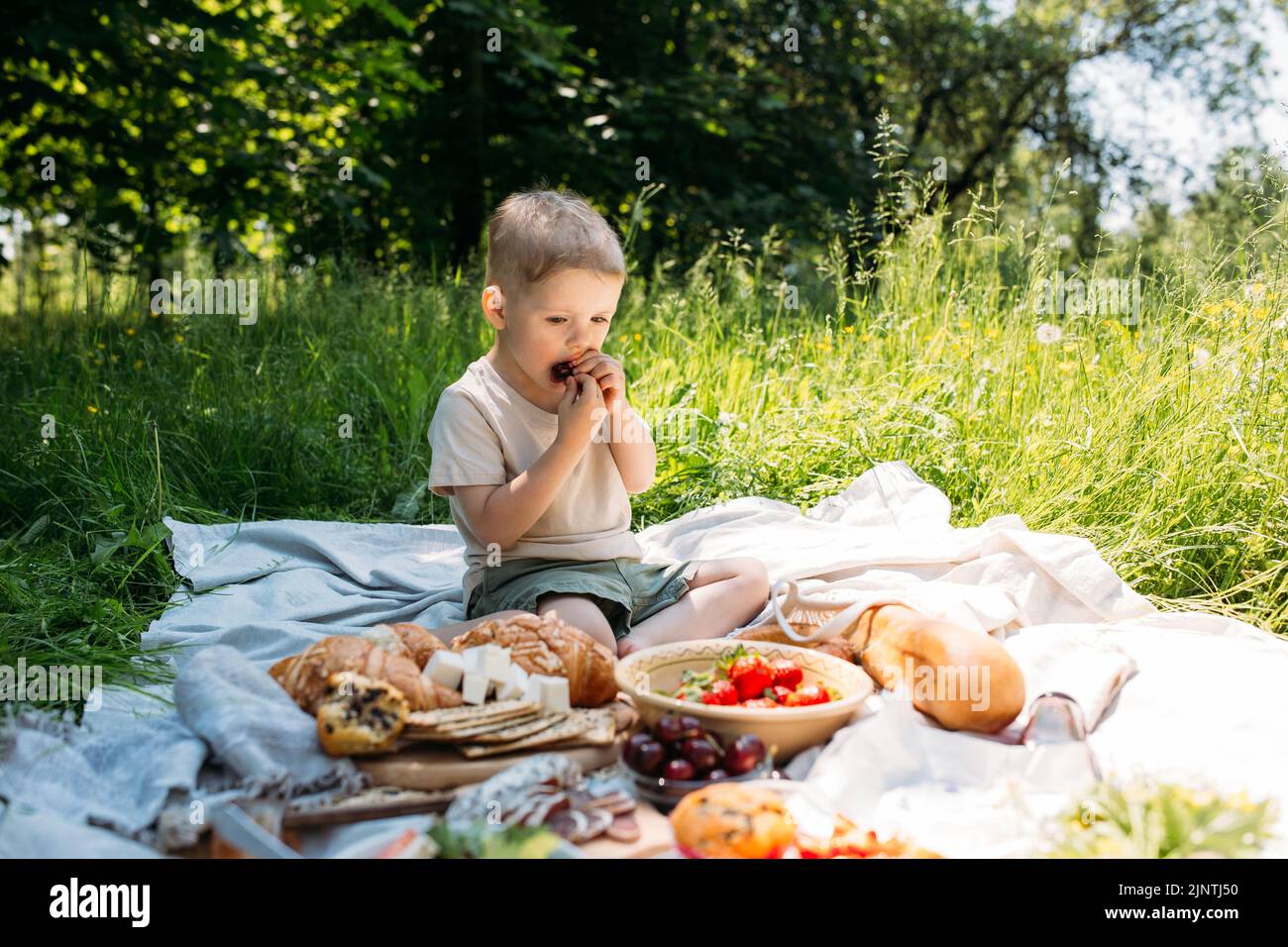 Junge Kind Vorschulkinder auf einem Picknick. Lächelt, Kirschen isst und den Sommer genießt. Stockfoto