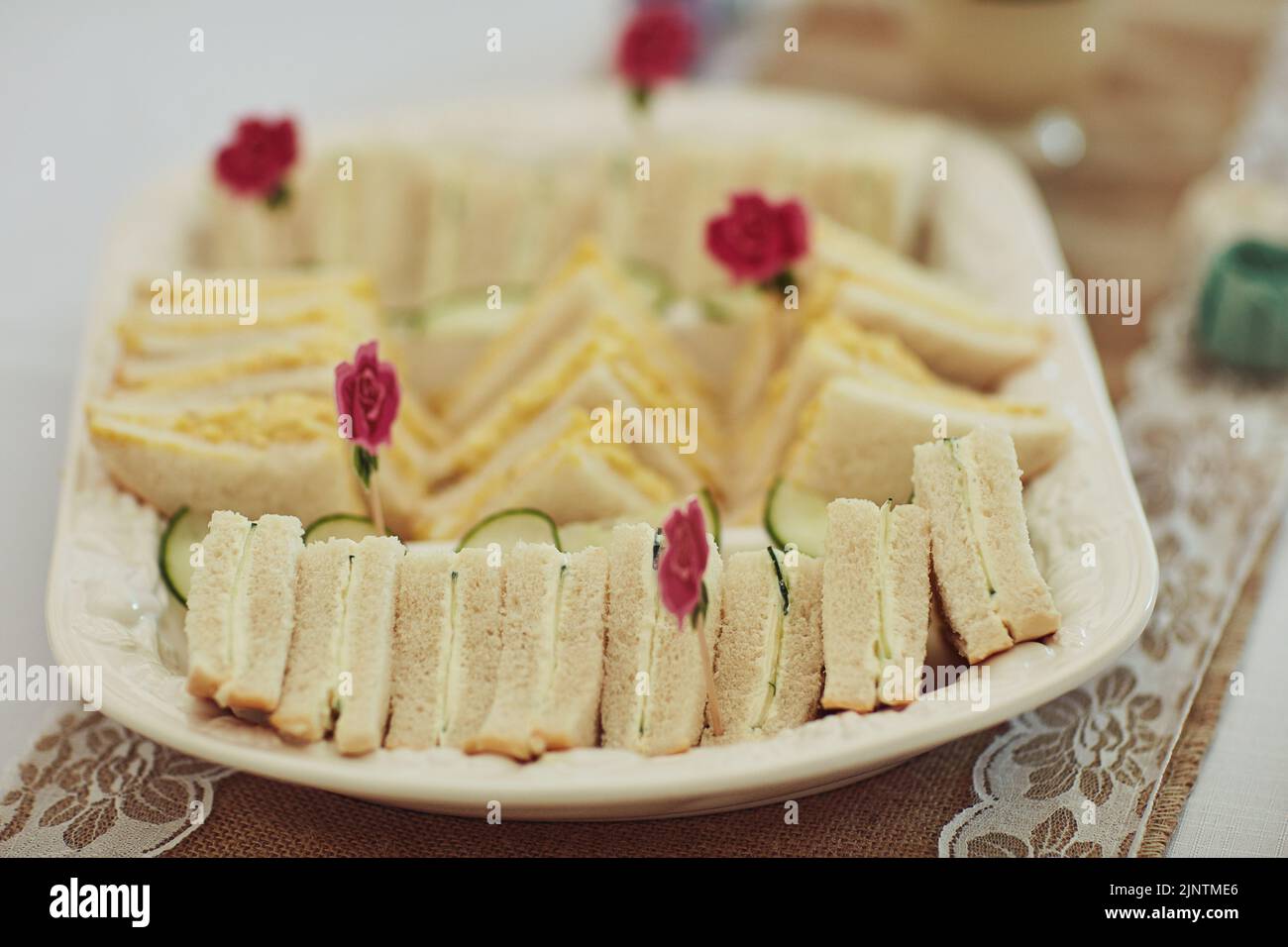 Teepartys werden nicht das gleiche sein ohne einen Sandwich-Snack. Dreieckige Sandwiches auf einem Tisch bei einer Teeparty im Inneren. Stockfoto