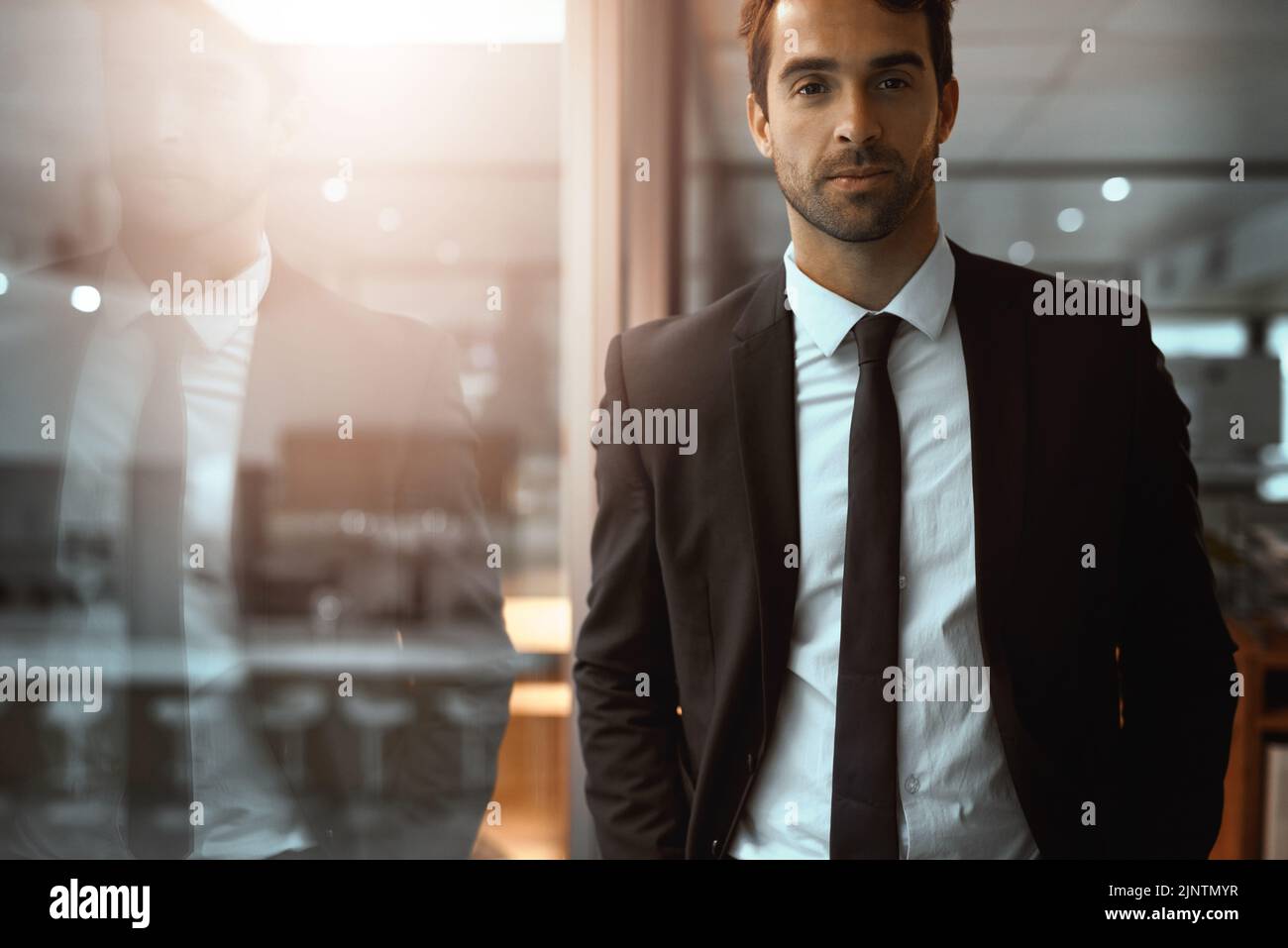 In seinem erfolgreichen Imperium hoch stehend. Porträt eines jungen Geschäftsmannes, der in einem Büro steht. Stockfoto