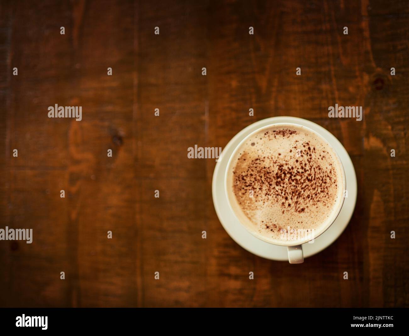 Der perfekte Start in den Morgen. Eine frisch gebrühte Tasse Kaffee, die in einem Restaurant auf einem Tisch neben dem eigenen steht, ist in einem hohen Winkel aufgenommen worden. Stockfoto