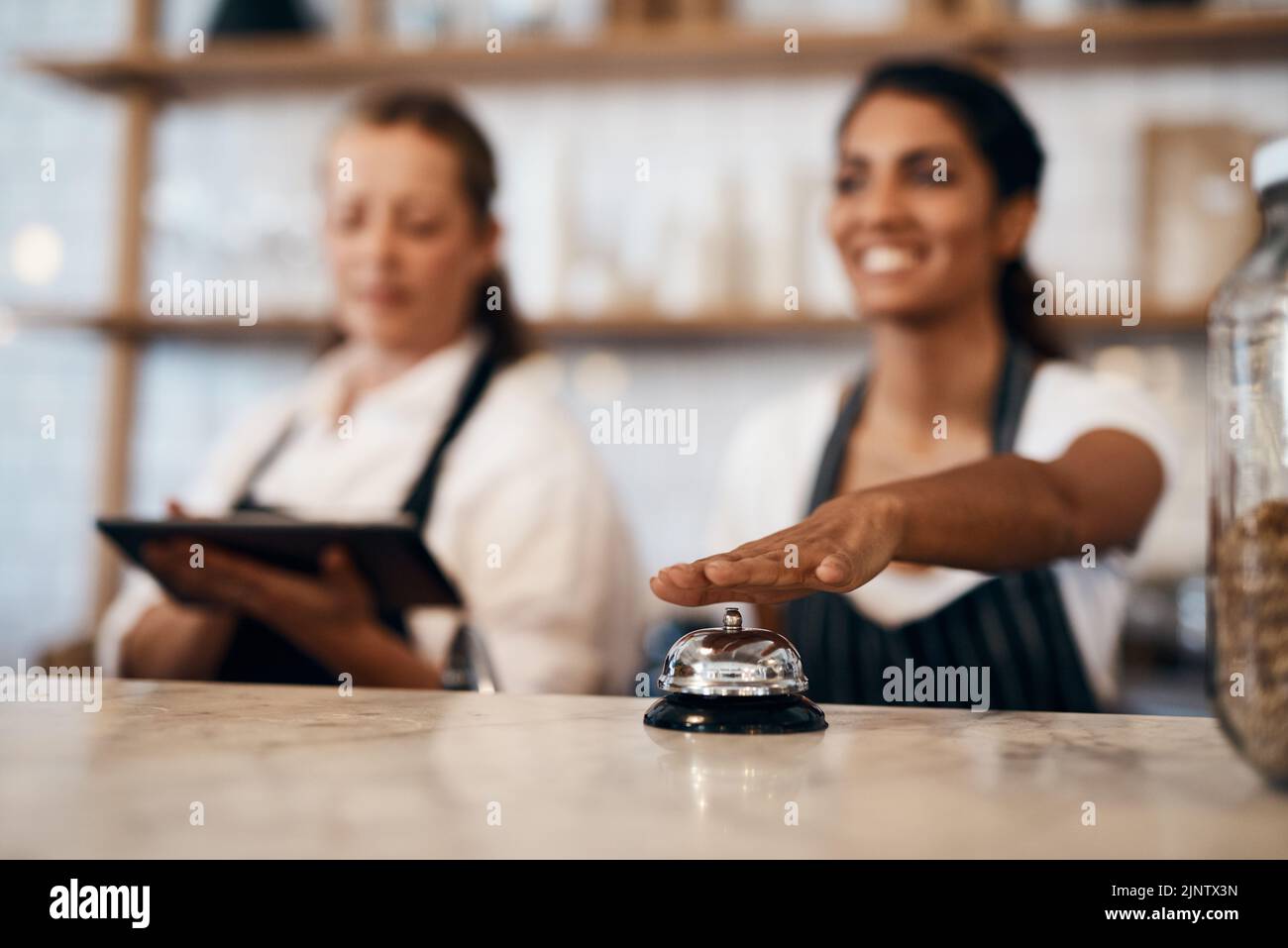 Die Kellnerin gibt im Café, Restaurant und Café eine klingelnde Klingel für eine fertige Bestellung. Kellnerinnen, Kellner und Baristas, die dienen, helfen oder Stockfoto