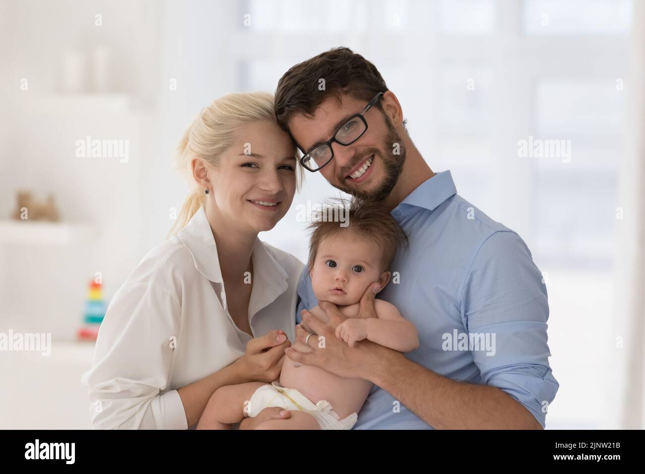 Porträt von liebevollen Eltern und Neugeborenen, die die Kamera anstarren Stockfoto