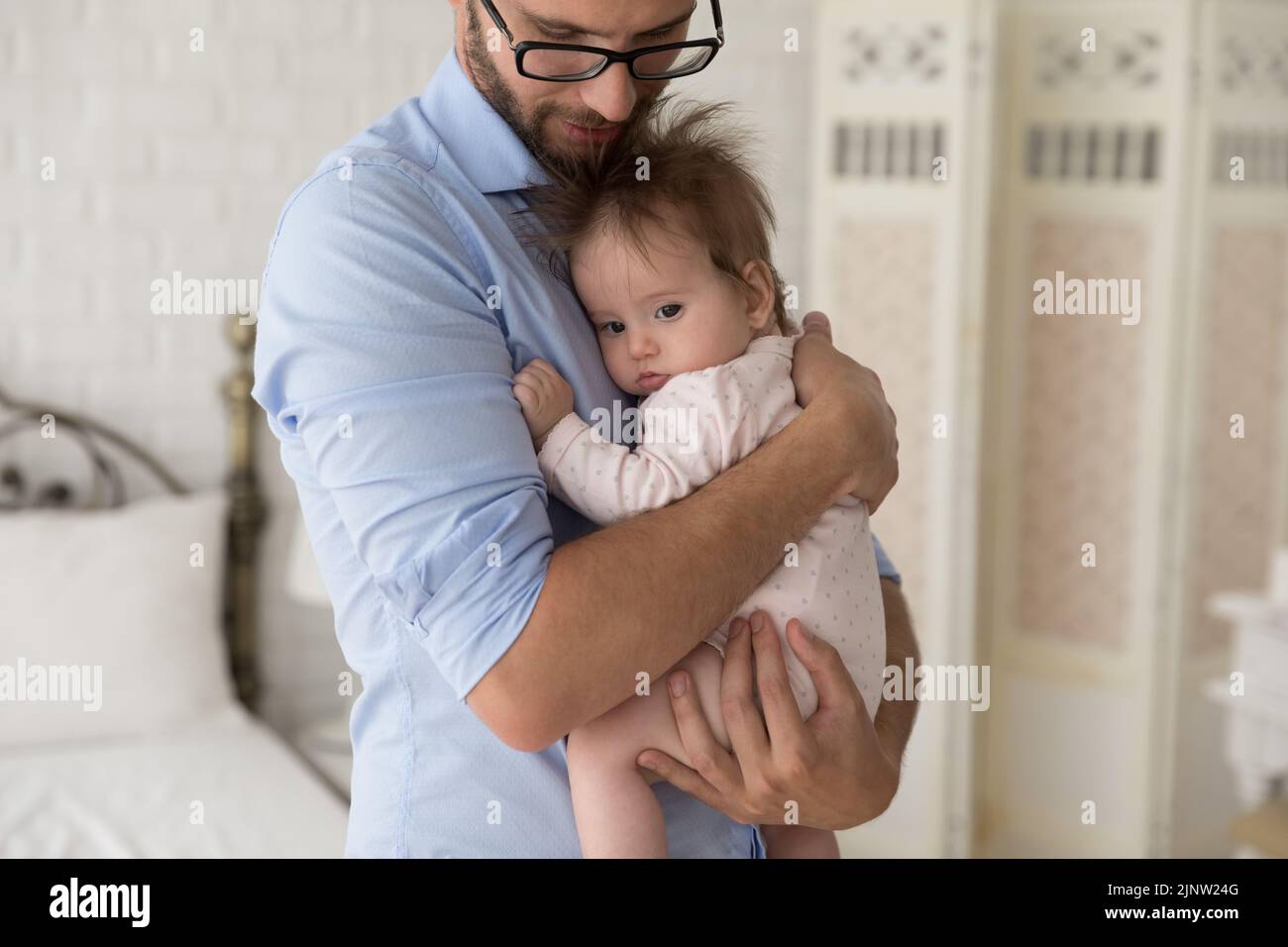 Fürsorglicher Vater beruhigt seine niedliche Tochter auf den Armen Stockfoto