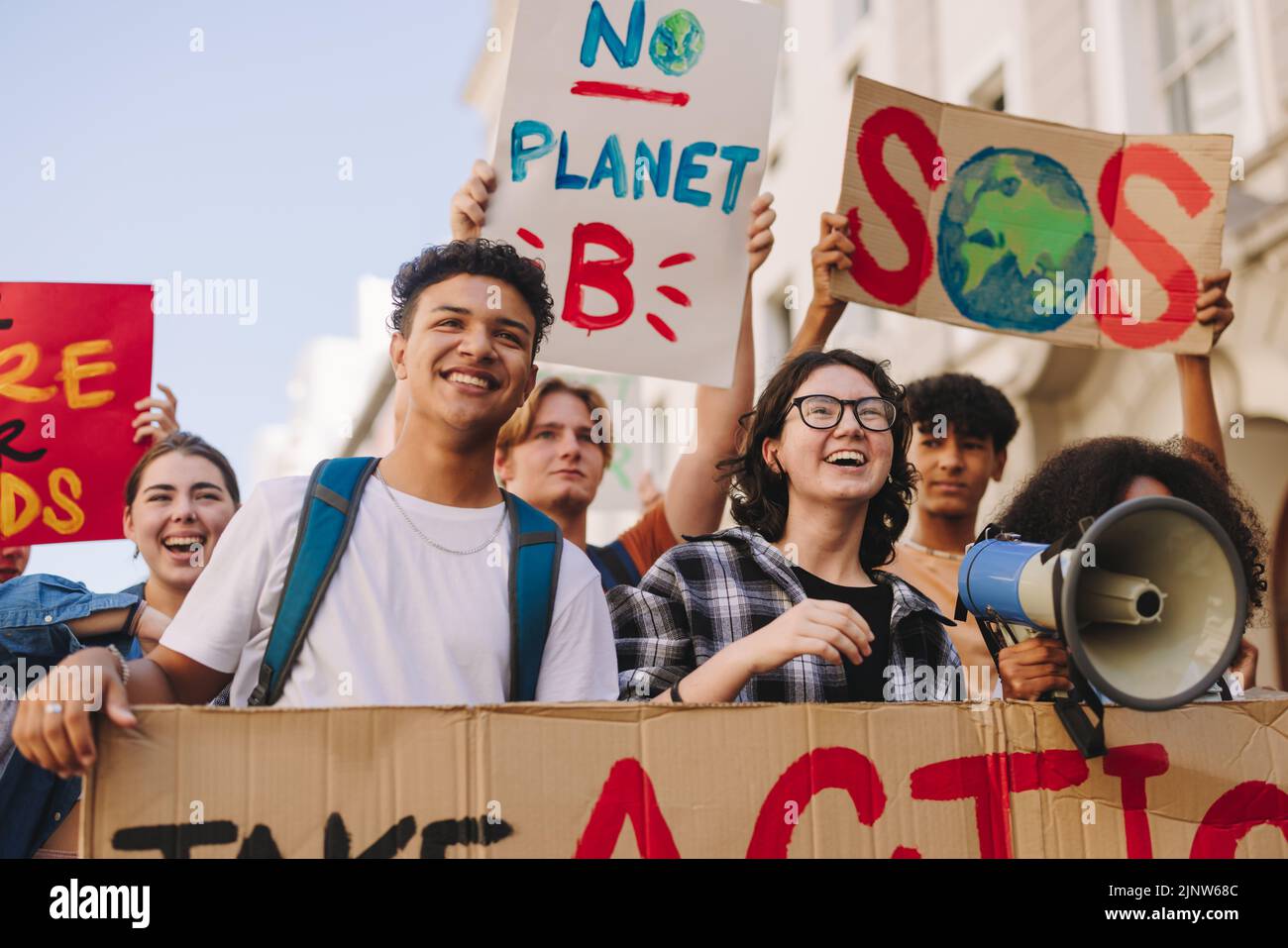 Umweltaktivismus der Generation Z. Glückliche junge Menschen mit Plakaten und Spruchbändern, während sie gegen den Klimawandel marschieren. Multikulturelle Jugendarbeit Stockfoto