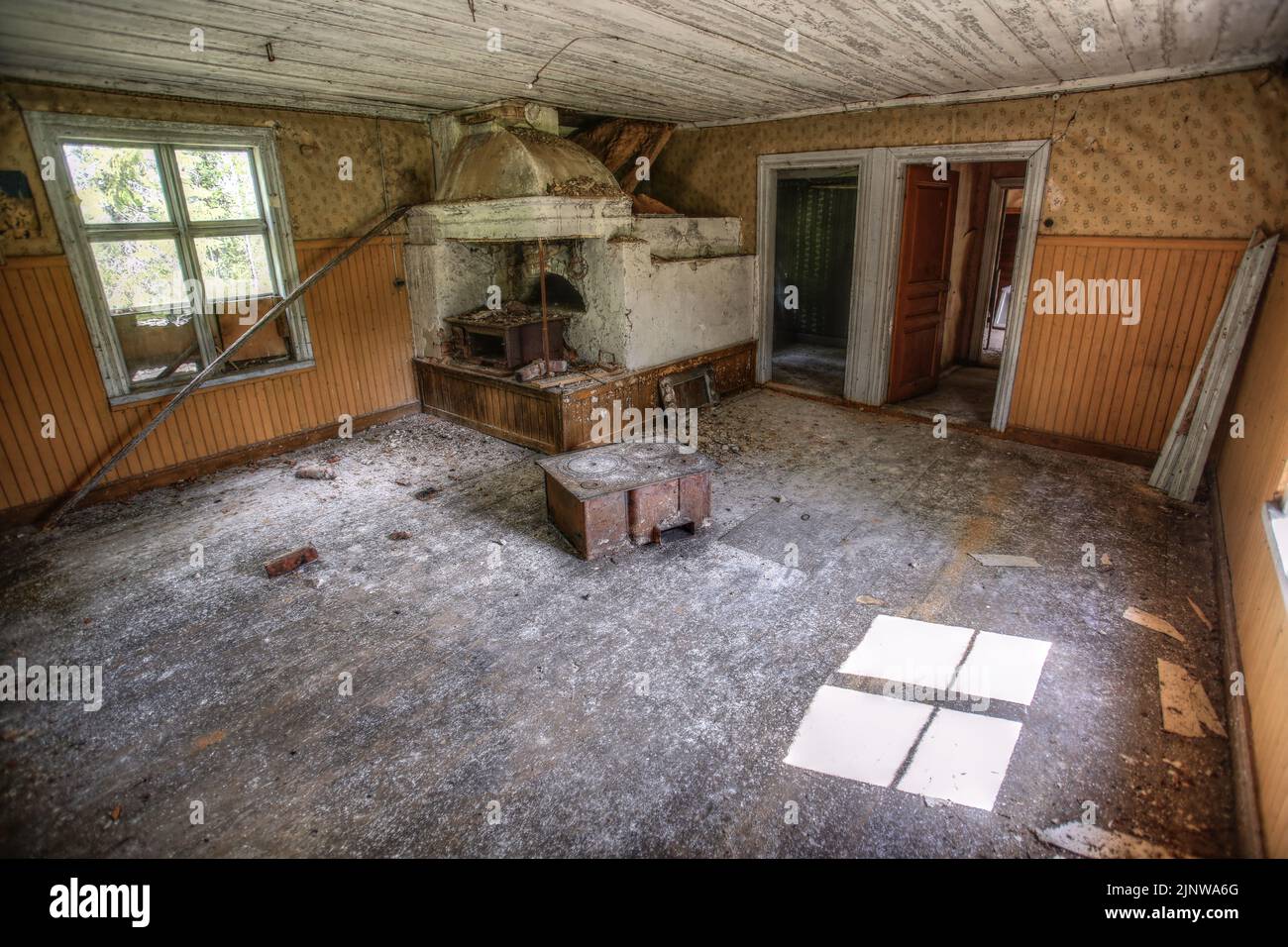 Das Innere eines alten Holzhauses mit rostigen Öfen ist ruiniert. Stockfoto
